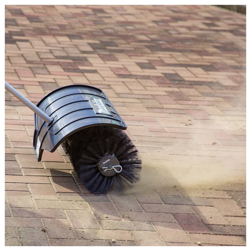 Ein Kehrbesen dreht sich und fegt Staub von Pflastersteinen, die ineinander greifen, um die Oberfläche sauber zu halten.