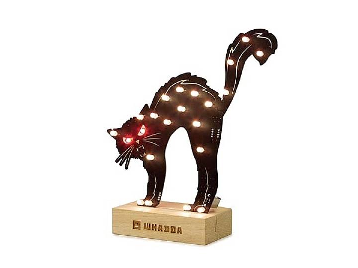 Schwarze Katzenlampe aus Holz mit roten Augen, die auf einem Holzsockel steht. Leuchtet mit mehreren kleinen Glühbirnen.