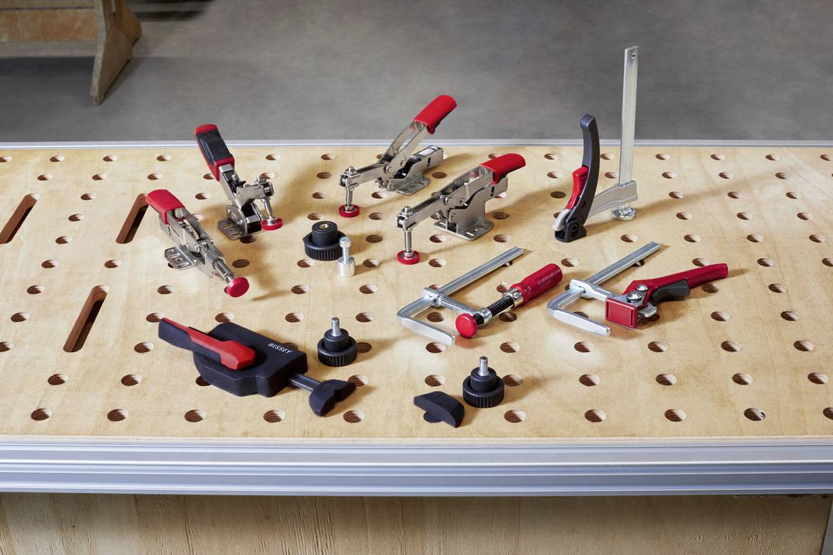 Verschiedene Werkzeuge und Klemmen sind auf einer perforierten Holzplatte angeordnet, bereit für den Einsatz in der Werkstatt.