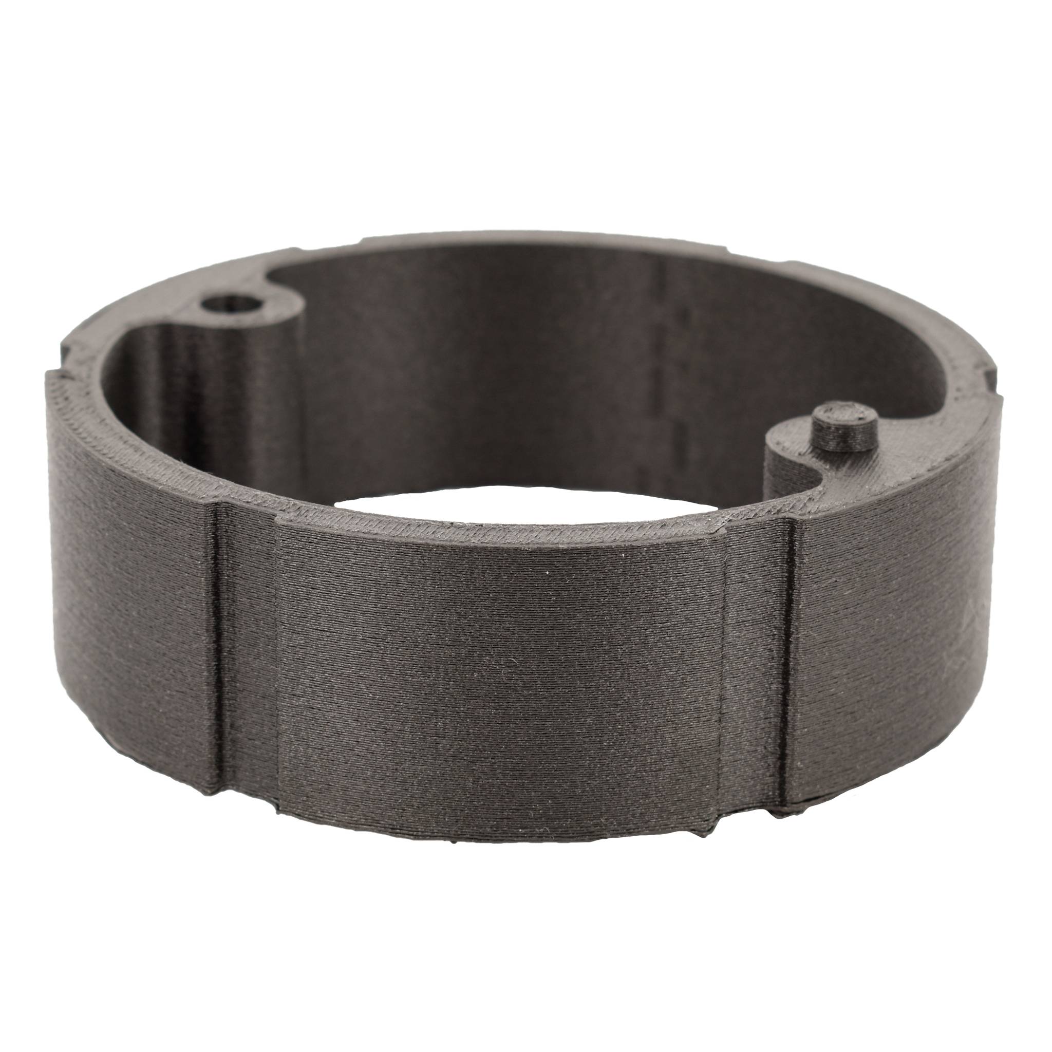 Ein zylindrisches, schwarz-graues Maschinenteil aus Metall mit glatter Oberfläche und zwei kleinen Aussparungen an einer Seite.