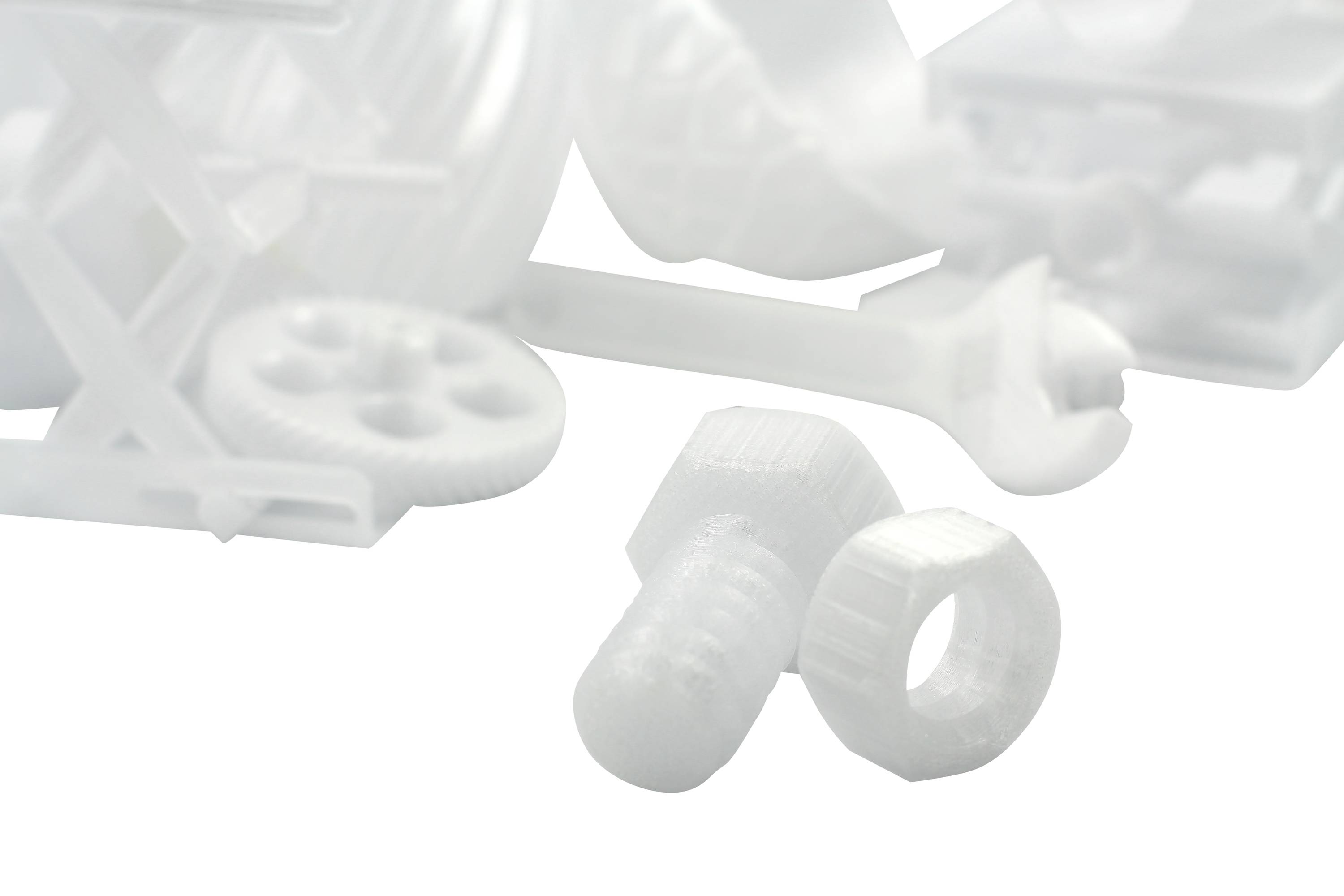 Weiße 3D-gedruckte Objekte: Schraube, Mutter, Zahnräder, Schraubenschlüssel und diverse Bauteile. Sie symbolisieren Technik und Innovation.