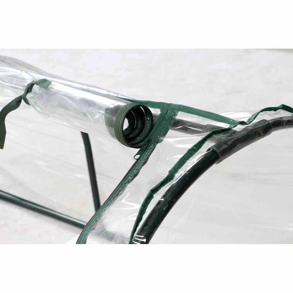 Nahaufnahme eines aufgerollten Kunststofffensters mit grünem Rahmen, Teil eines Gewächshauses.