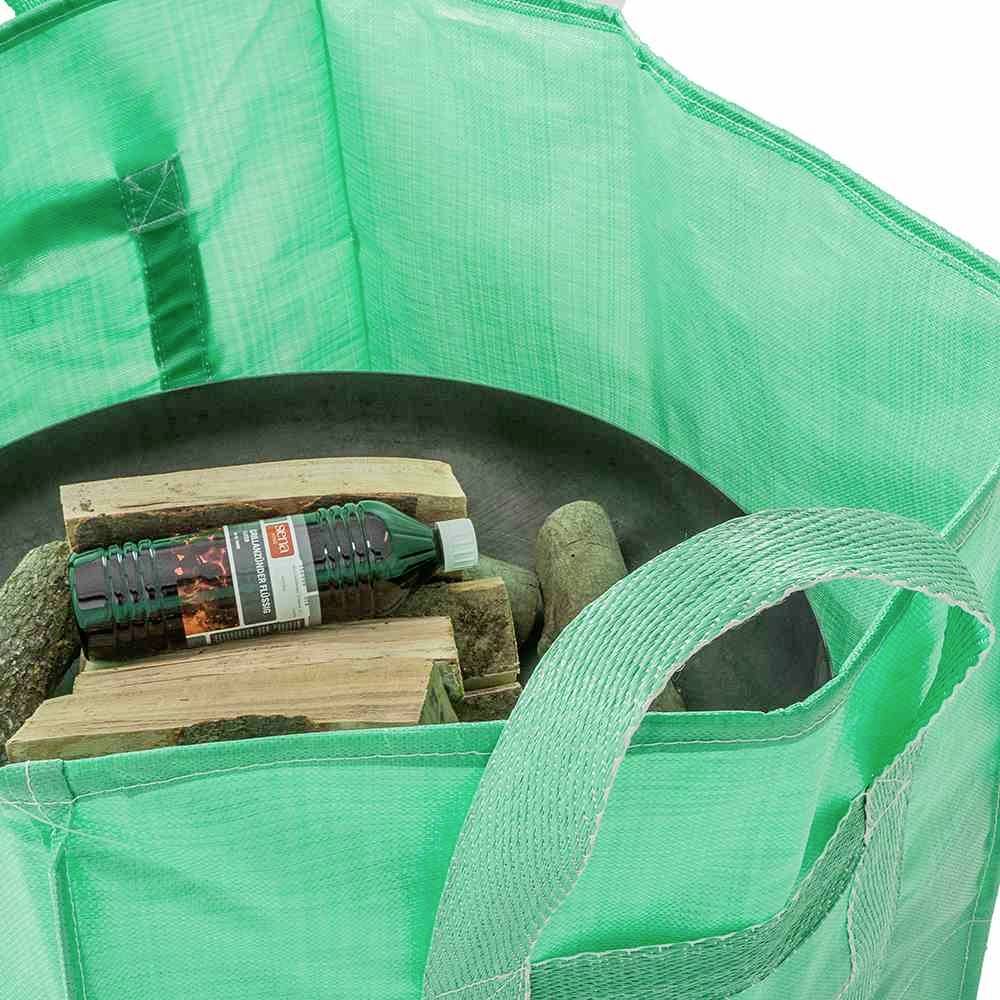 Eine grüne, offene Tasche enthält Holzscheite und eine Flasche Grillanzünder.