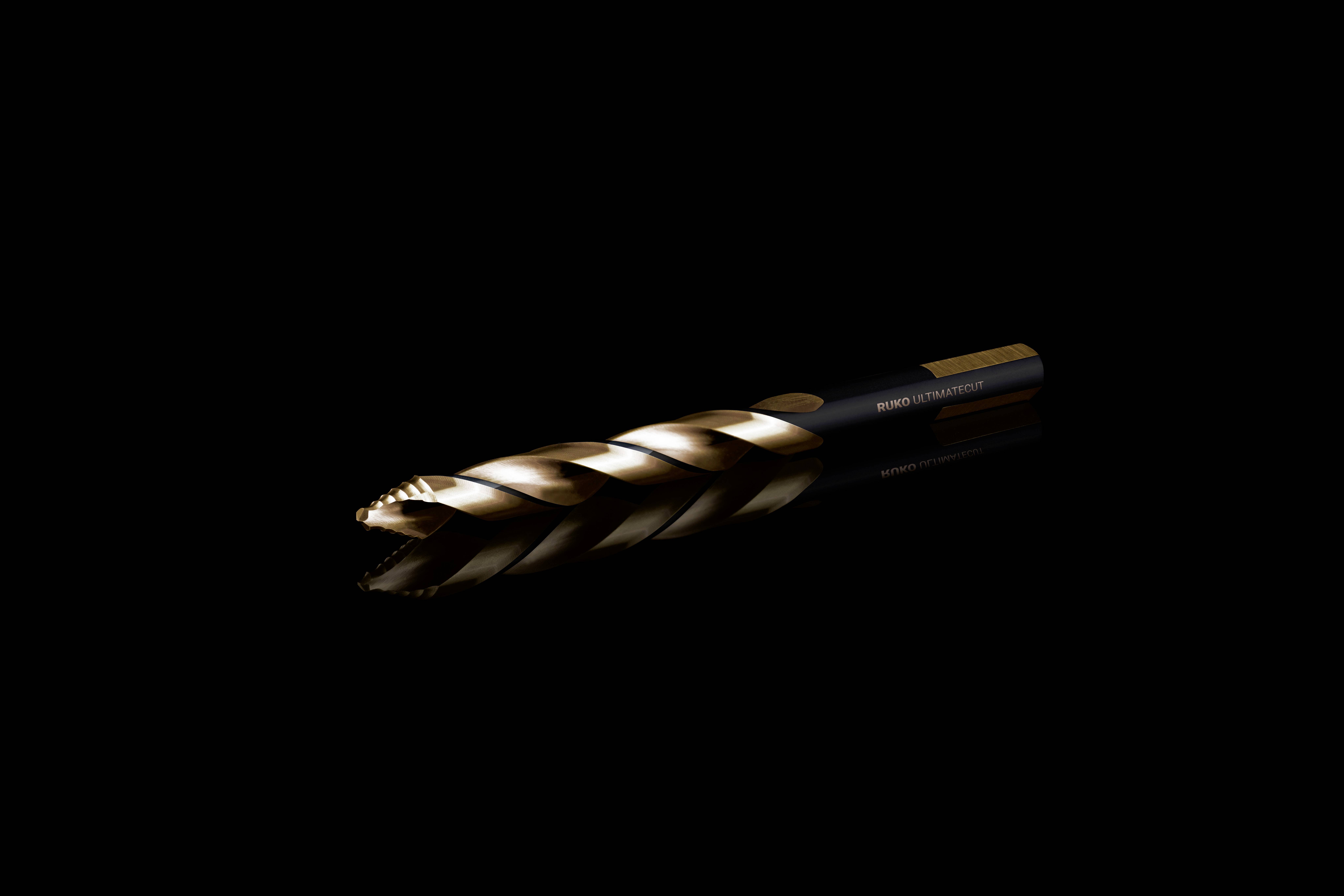 Ein goldfarbener Spiralbohrer vor schwarzem Hintergrund, diagonal ausgerichtet. Er reflektiert das Licht und zeigt Details der Schneidekanten.