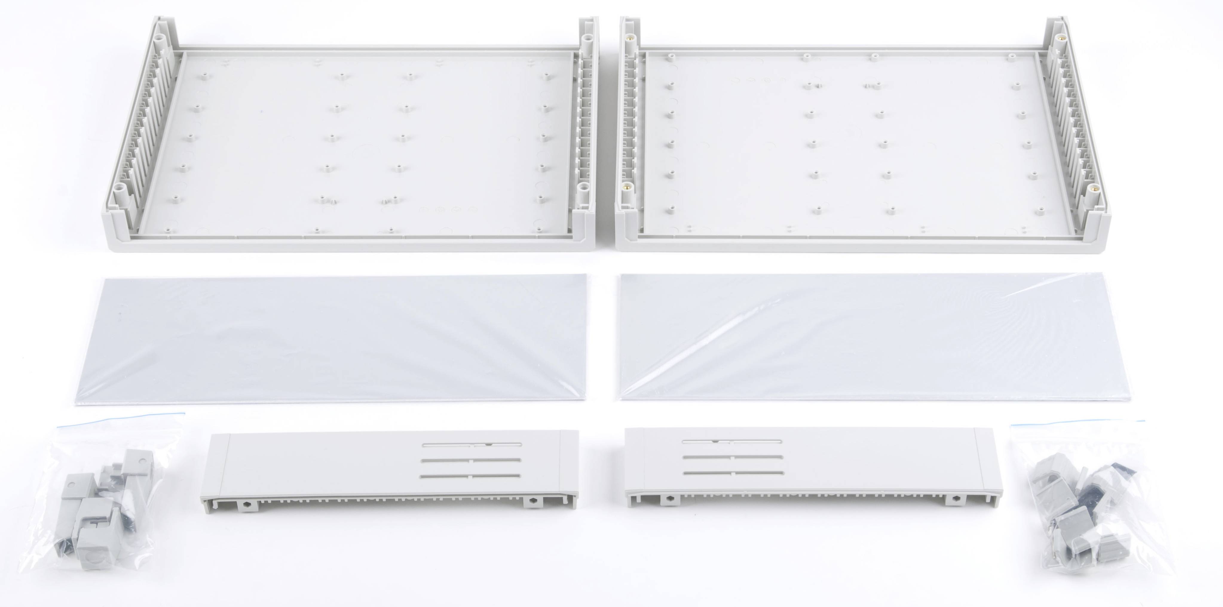 Zubehörset für ein Gehäuse bestehend aus zwei großen Metallplatten, zwei kleineren Abdeckungen und mehreren Plastikteilen in Tüten.