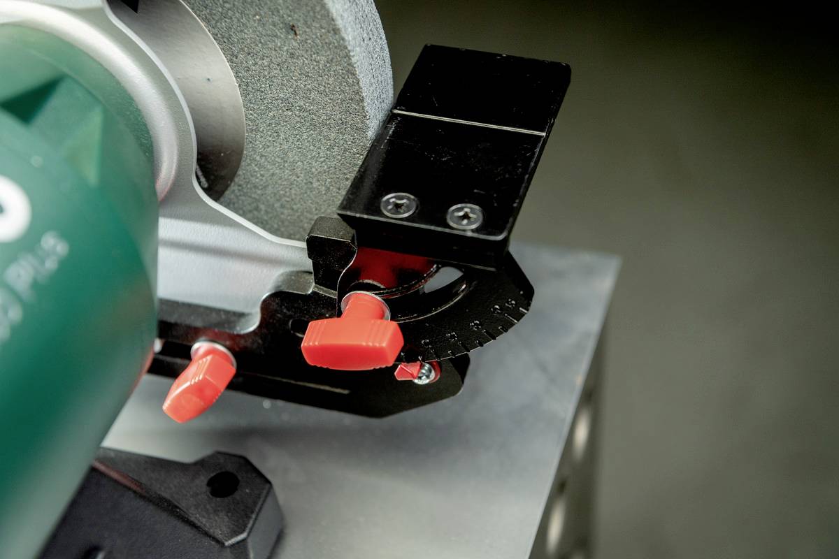 Eine Schleifmaschine mit rotem Einstellknopf. Die Maschine steht auf einem grauen Tisch und ist bereit für die Bearbeitung von Materialien.