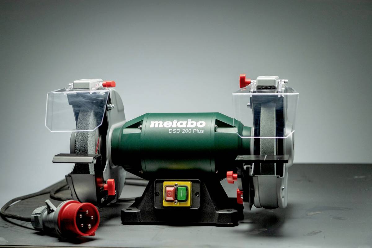Doppelschleifmaschine mit zwei Schleifscheiben, grünem Gehäuse, roten Bedienelementen und Sicherheitsabdeckungen; Marke 'Metabo DSD 200 Plus'.