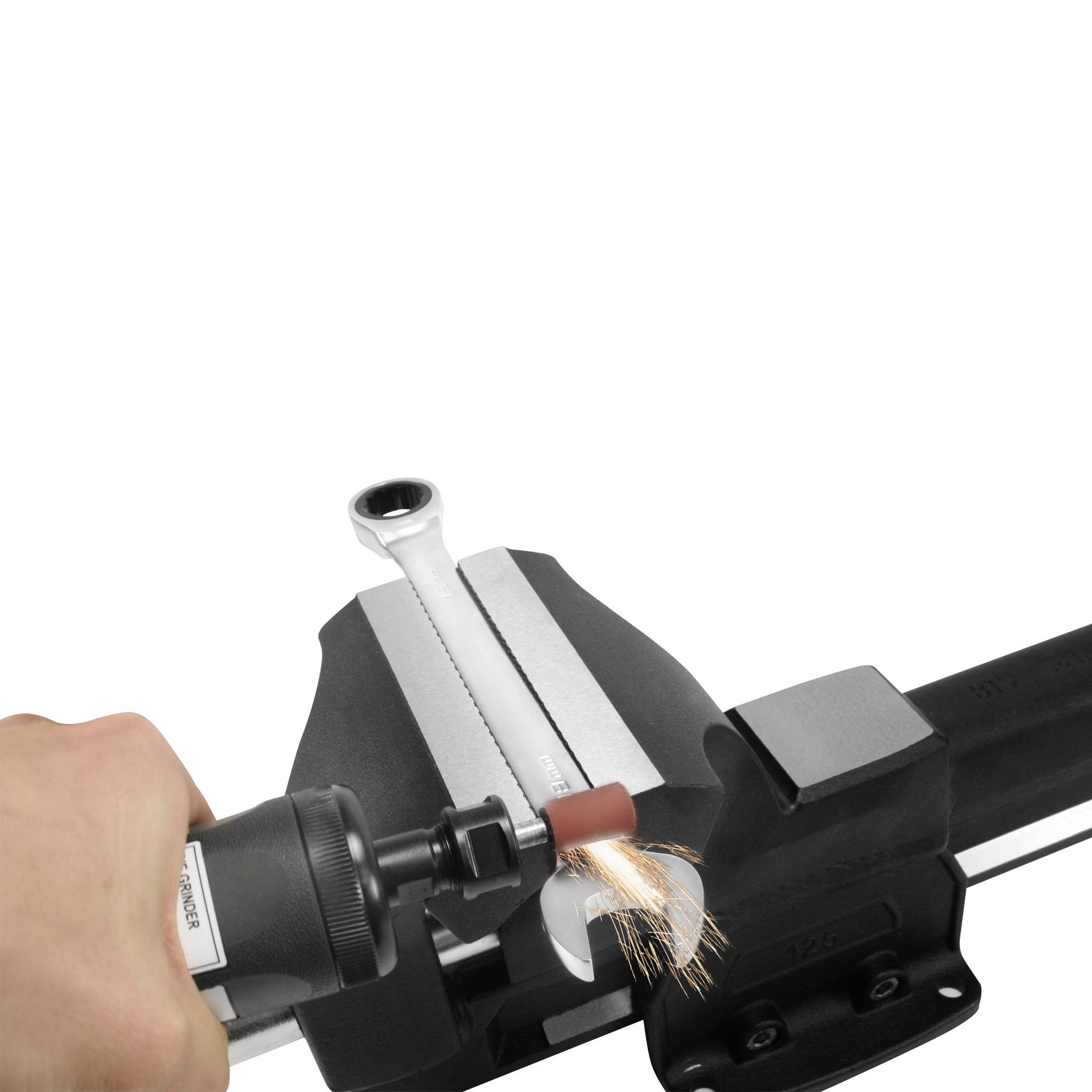 Eine Hand hält ein rotierendes Schleifwerkzeug, das Funken erzeugt, während es über ein Metallstück in einem Schraubstock geschliffen wird.
