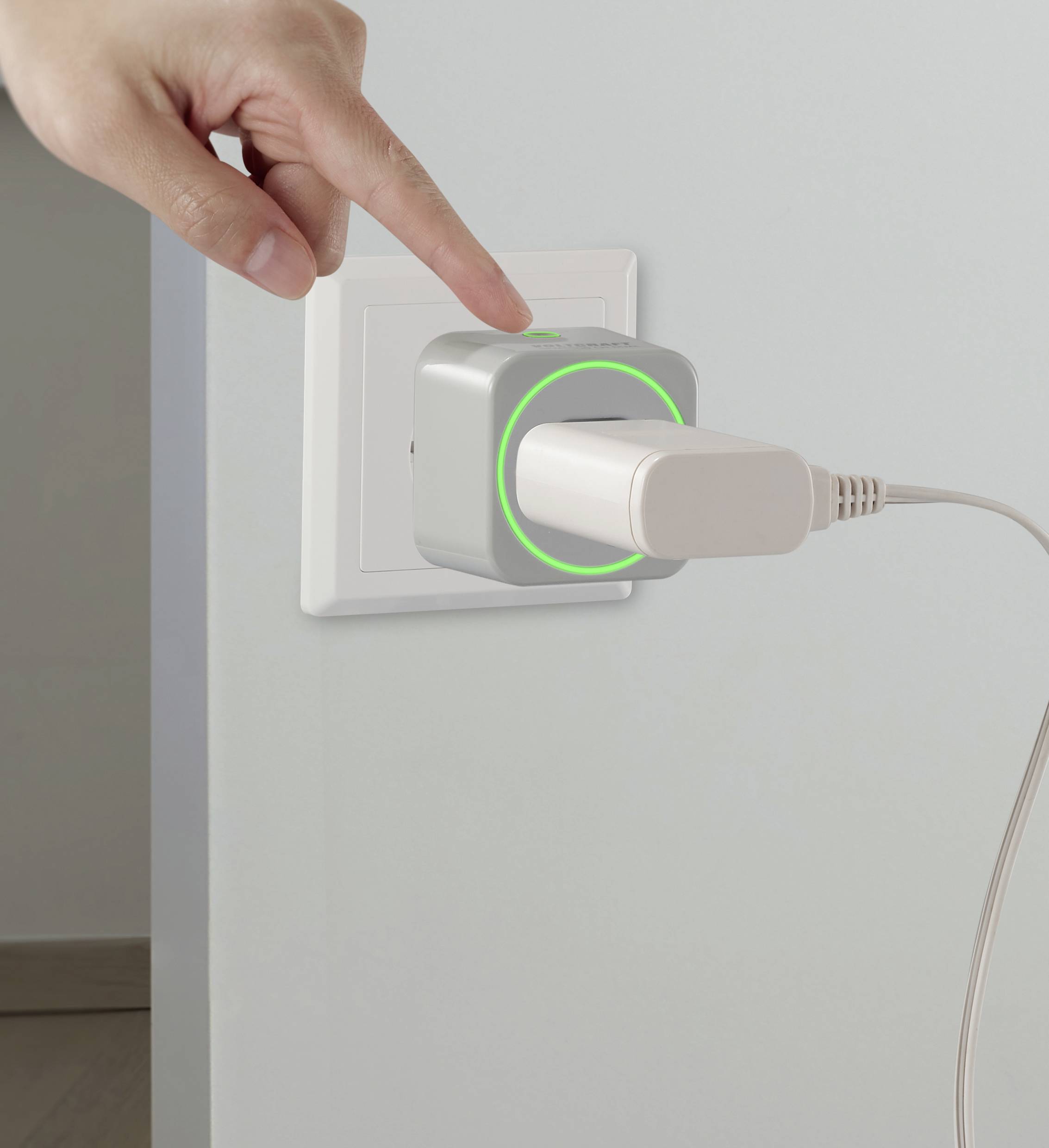 Eine Hand zeigt auf einen in die Steckdose gesteckten Adapter, der mit einem USB-Kabel verbunden ist. Ein grünes Licht leuchtet am Adapter.