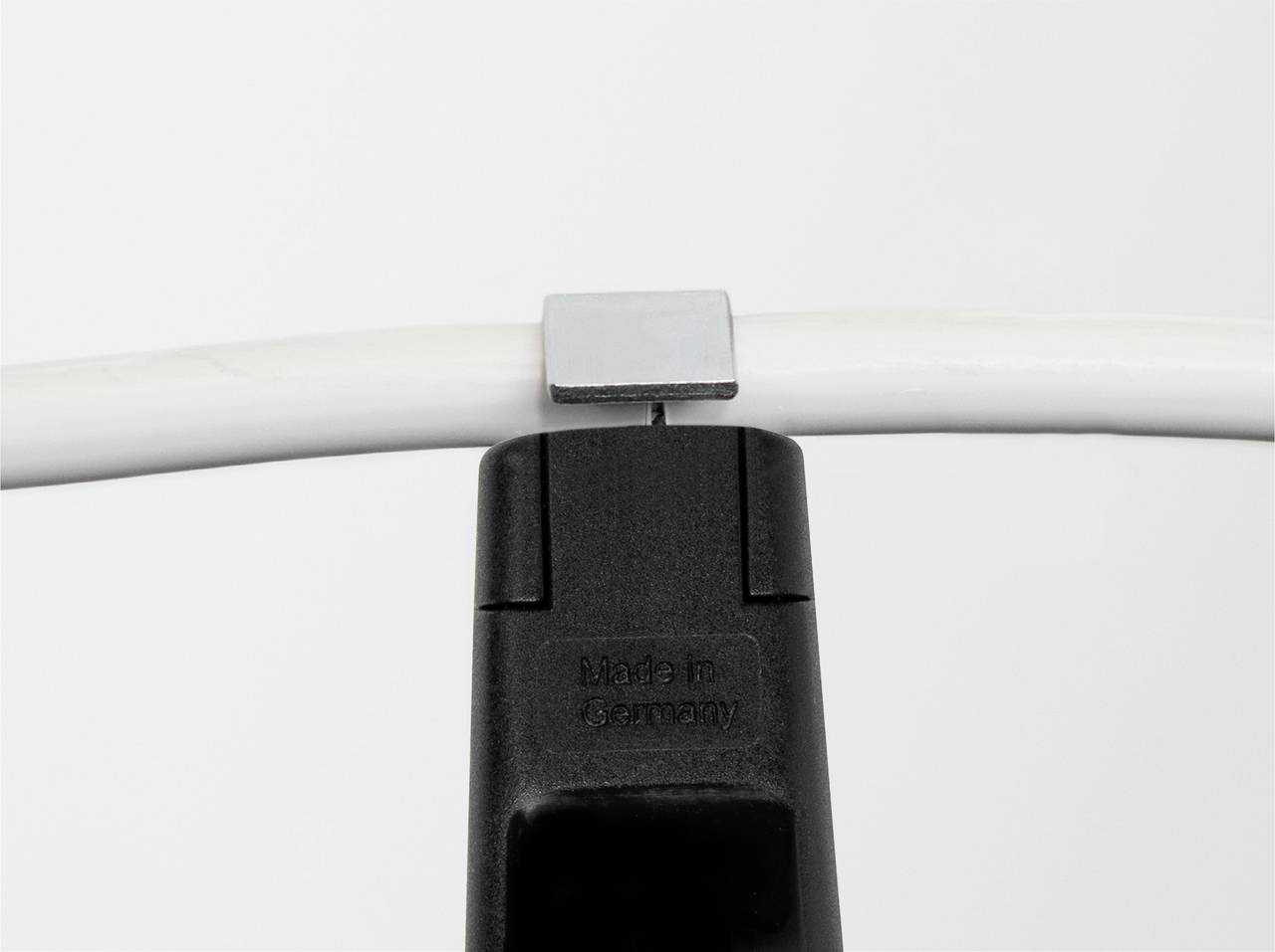 Ein schwarzer Ständer hält ein weißes Kabel. Auf dem Ständer steht 'Made in Germany'. Im Hintergrund ist ein neutraler, heller Hintergrund.