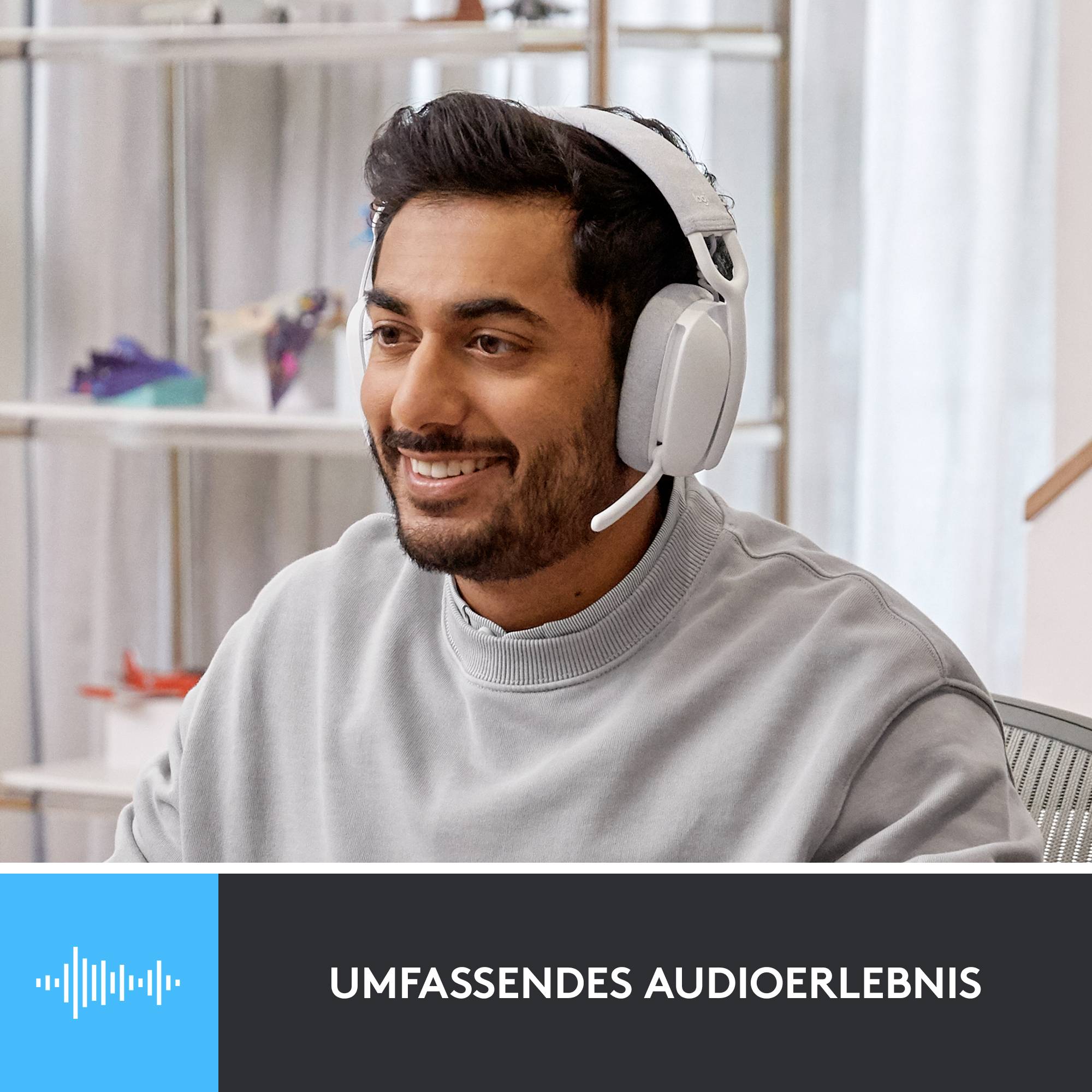 Eine Person mit Kopfhörern lächelt in einem modernen Raum. Unten steht 'Umfassendes Audioerlebnis'.