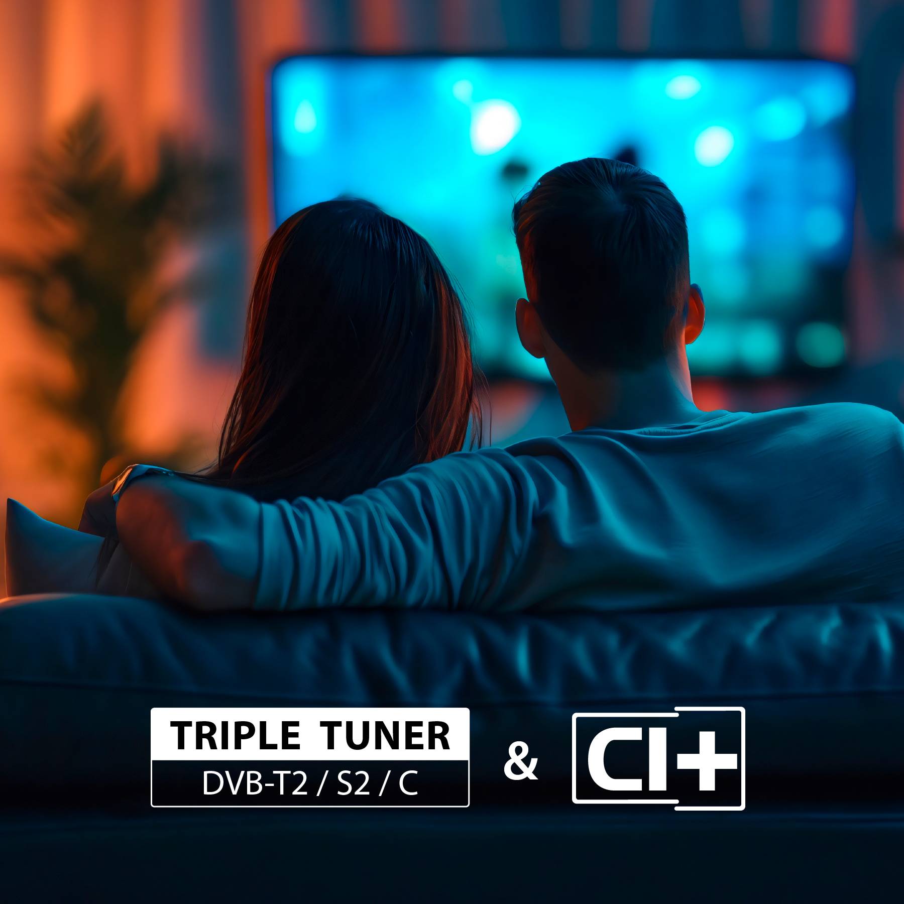 Ein Paar sitzt auf einem Sofa und schaut in einem schwach beleuchteten Raum fern. Der Overlay-Text lautet „Triple Tuner DVB-T2/S2/C & CI+