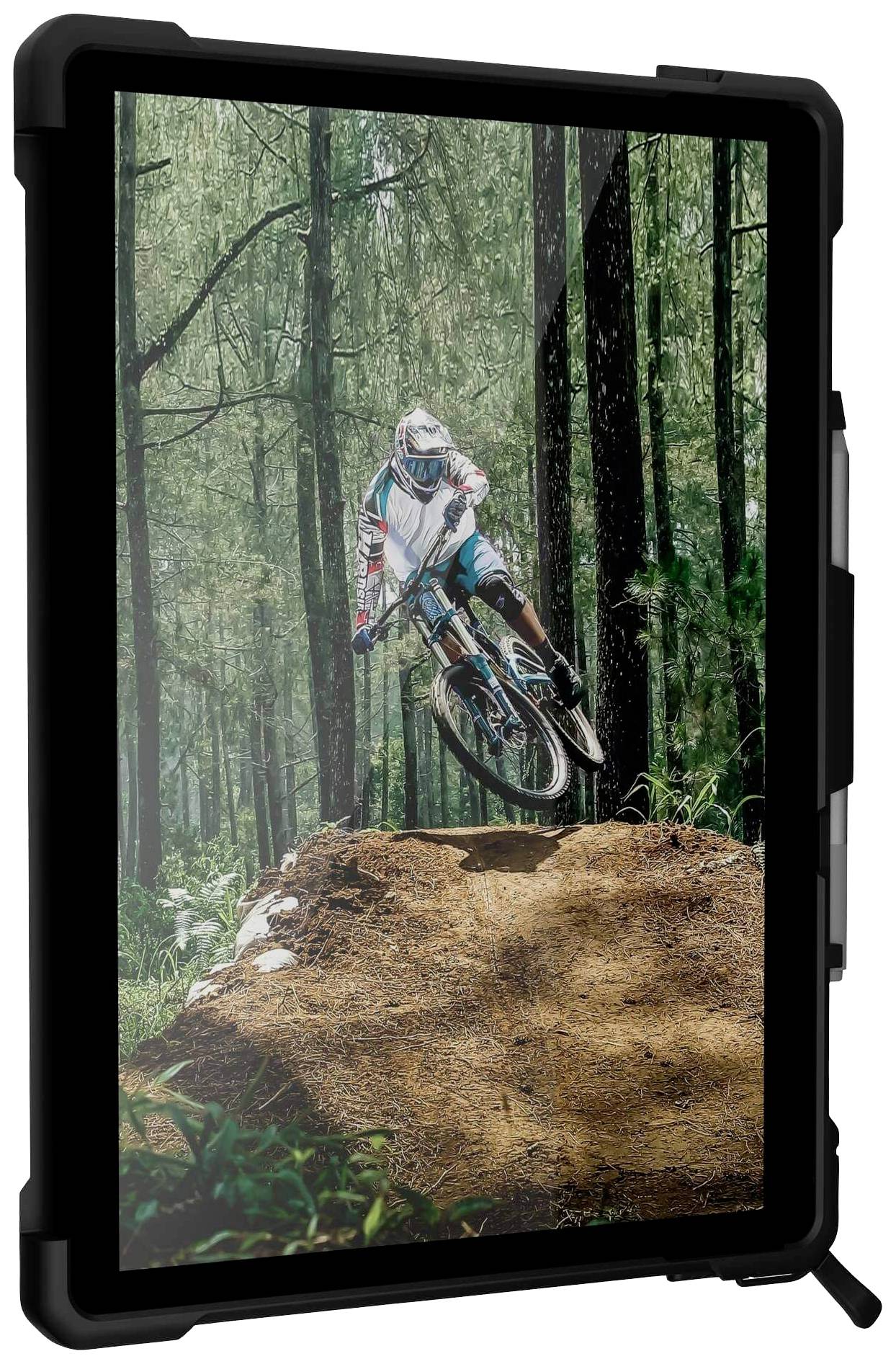 Ein Mountainbiker springt mit seinem Fahrrad über einen Erdhügel im Wald. Umgeben von hohen Bäumen und dichtem Grün.