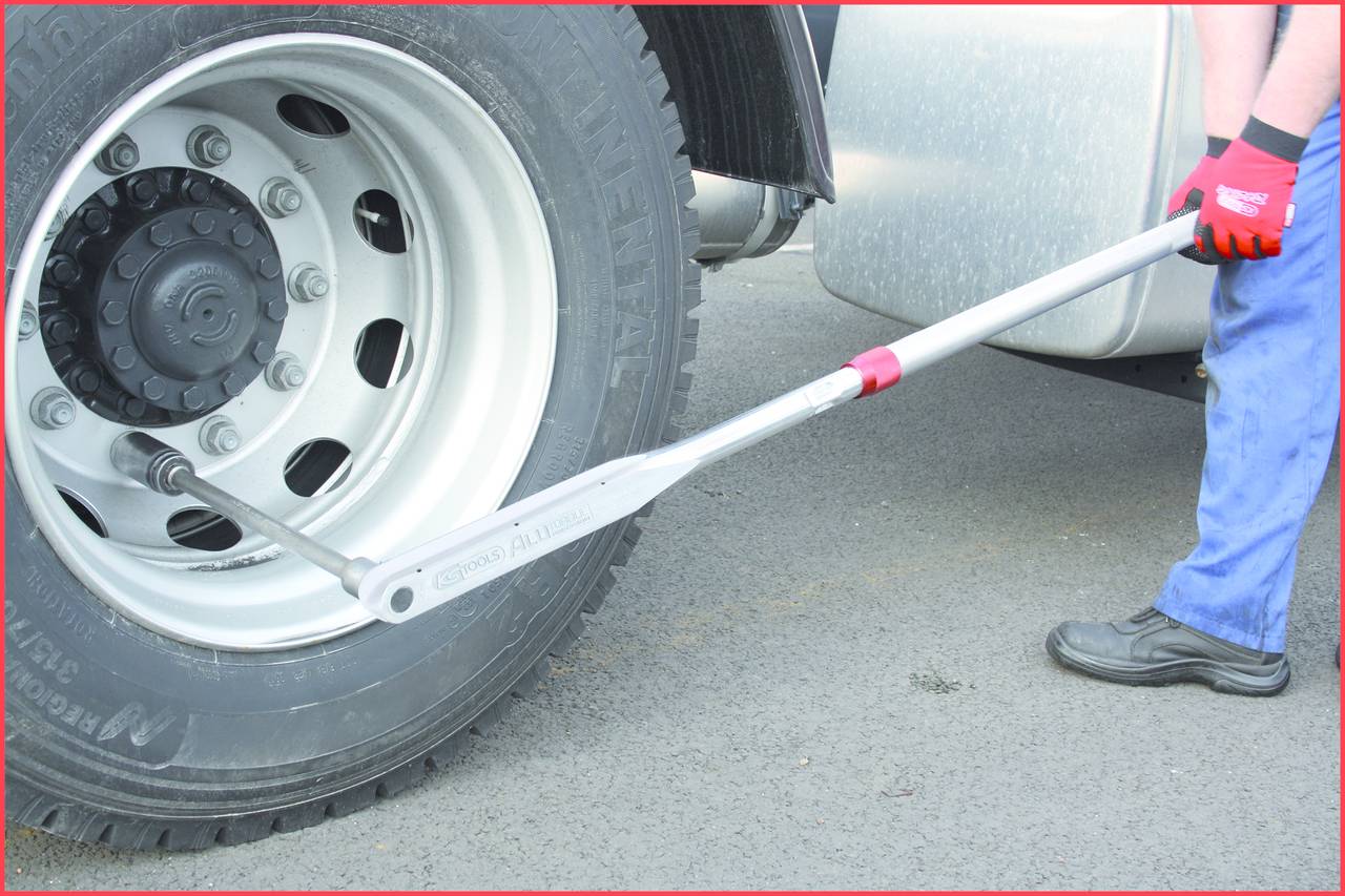 Person wechselt mit einem Spannschlüssel den Reifen eines Lastwagens. Der Spannschlüssel ist an der Radmutter angesetzt.