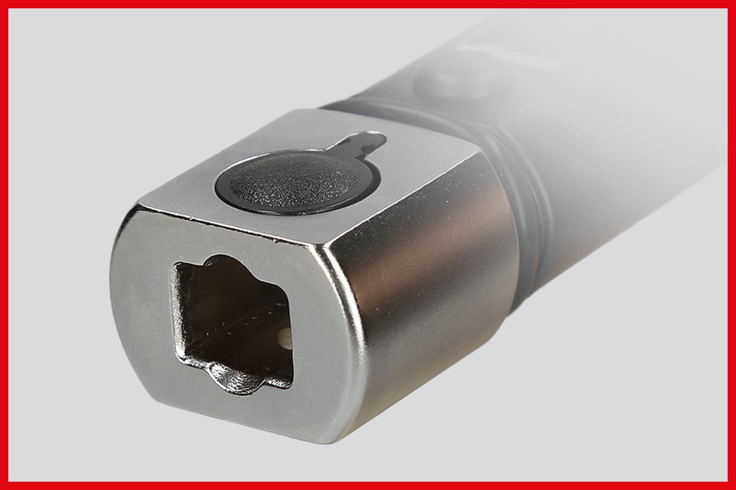 Nahaufnahme eines metallischen Werkzeugs mit quadratischer Öffnung und schwarzem Knopf. Es sind keine weiteren Details sichtbar.