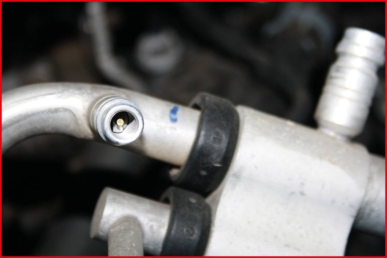 Nahaufnahme eines silbernen Metallrohrs mit zwei Gummihaltern, das Teil eines größeren mechanischen Systems ist. Im Hintergrund unscharf.