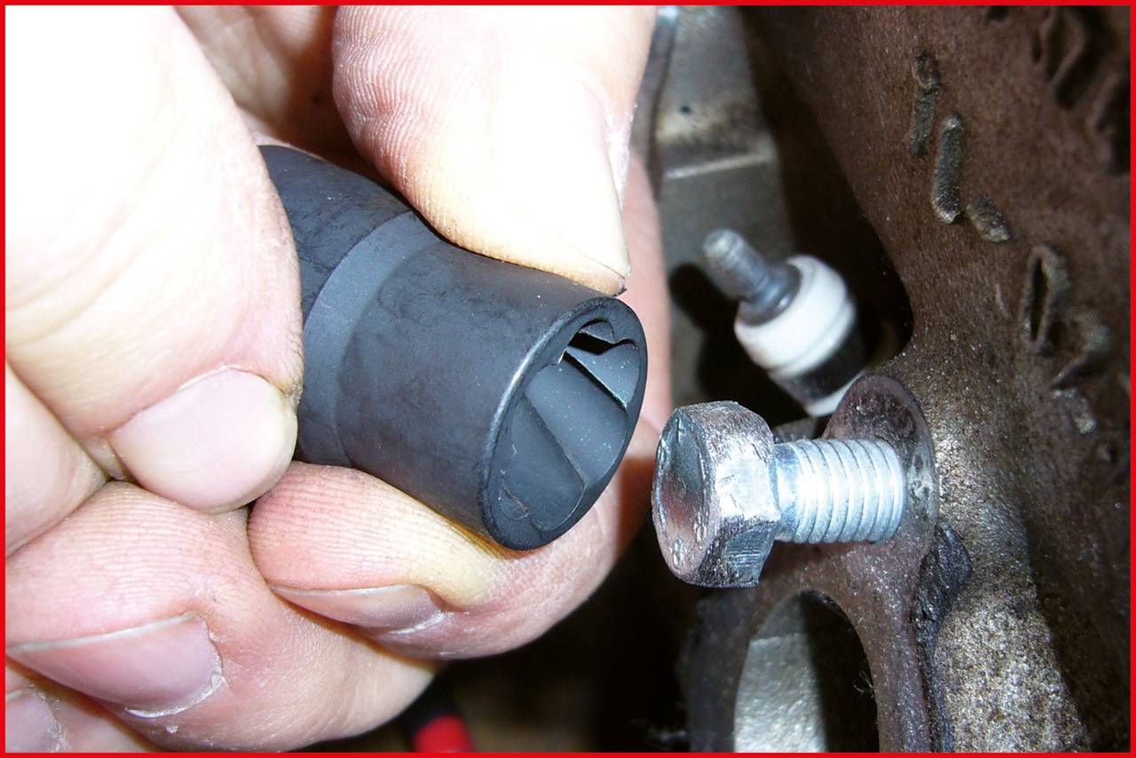Nahaufnahme von Händen, die einen Gummizapfen neben einer Metallschraube halten. Schraube in maschinell bearbeitetem Metallteil eingesetzt.