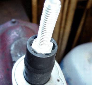 Nahaufnahme eines Metallschraubenschlüssels, der eine lange Schraube anzieht. Der Hintergrund ist unscharf.