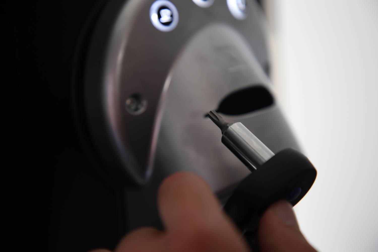 Eine Hand hält ein elektronisches Gerät vor ein Schloss mit beleuchteten Symbolen, möglicherweise ein Sicherheitszugangsgerät.