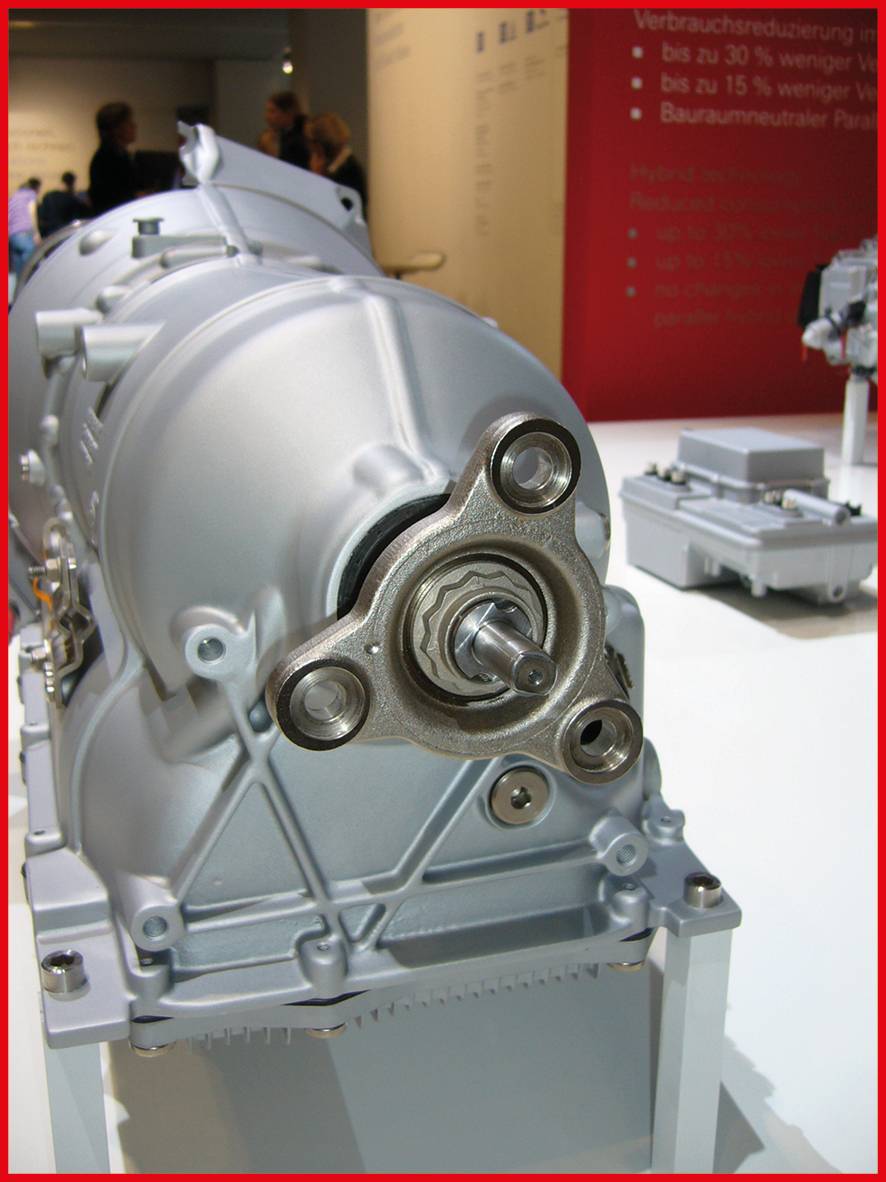 Getriebe aus Metall auf einer Ausstellung mit technischem Hintergrund und Informationsplakat im hinteren Bereich.
