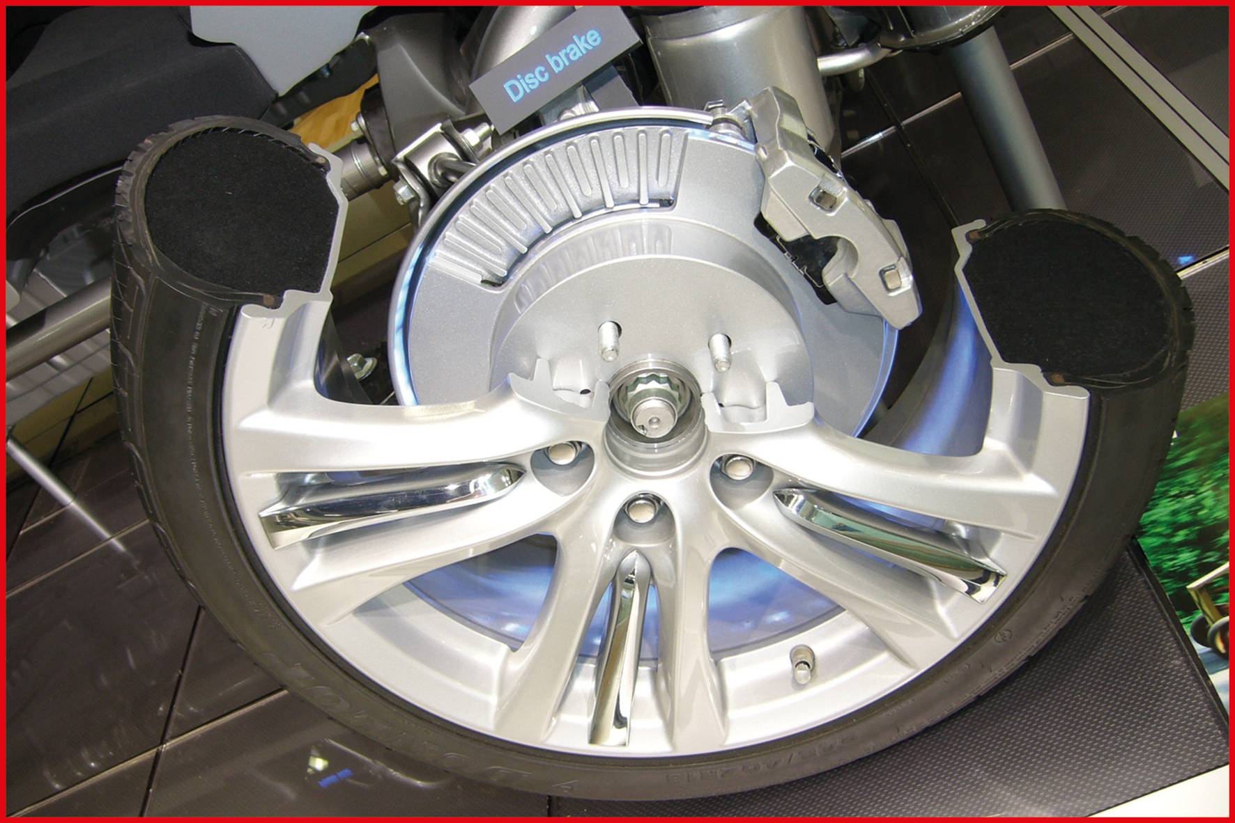 Ein Querschnitt eines Autoreifens zeigt die innenliegende Scheibenbremse und die Felge.