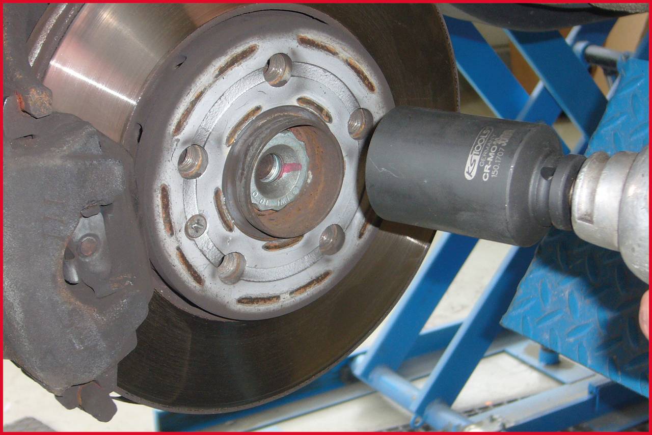 Nahaufnahme eines Bremsrotors, der mit einem Schlagschrauber bearbeitet wird, vermutlich in einer Werkstattumgebung.