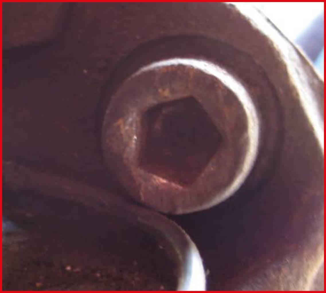 Nahaufnahme einer großen Sechskantschraube, teilweise in eine mechanische Vorrichtung eingebettet, mit metallisch glänzender Oberfläche.