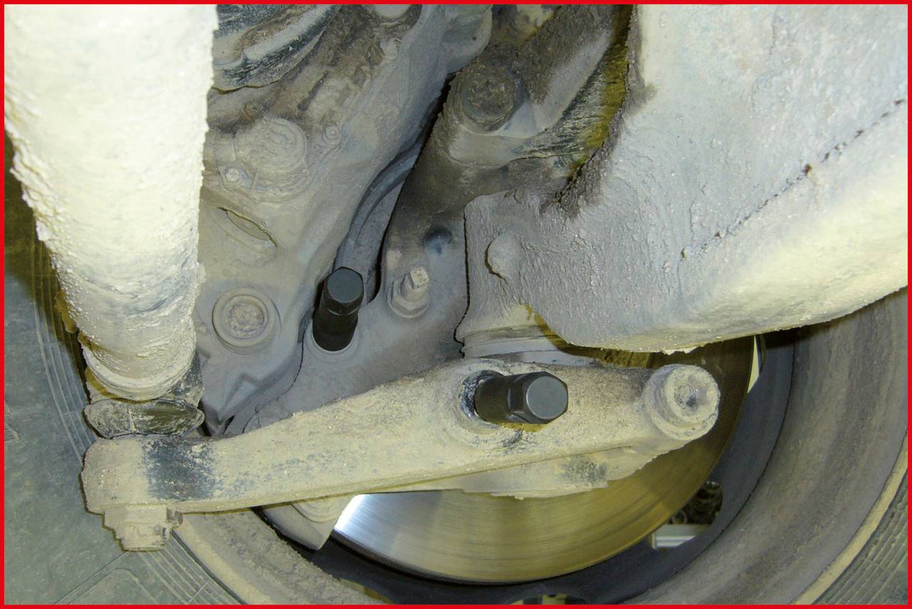 Nahaufnahme eines verschmutzten Fahrzeug-Radkastens mit sichtbarer Aufhängung und Bremsscheibe. Der Fokus liegt auf der technischer Zustand.