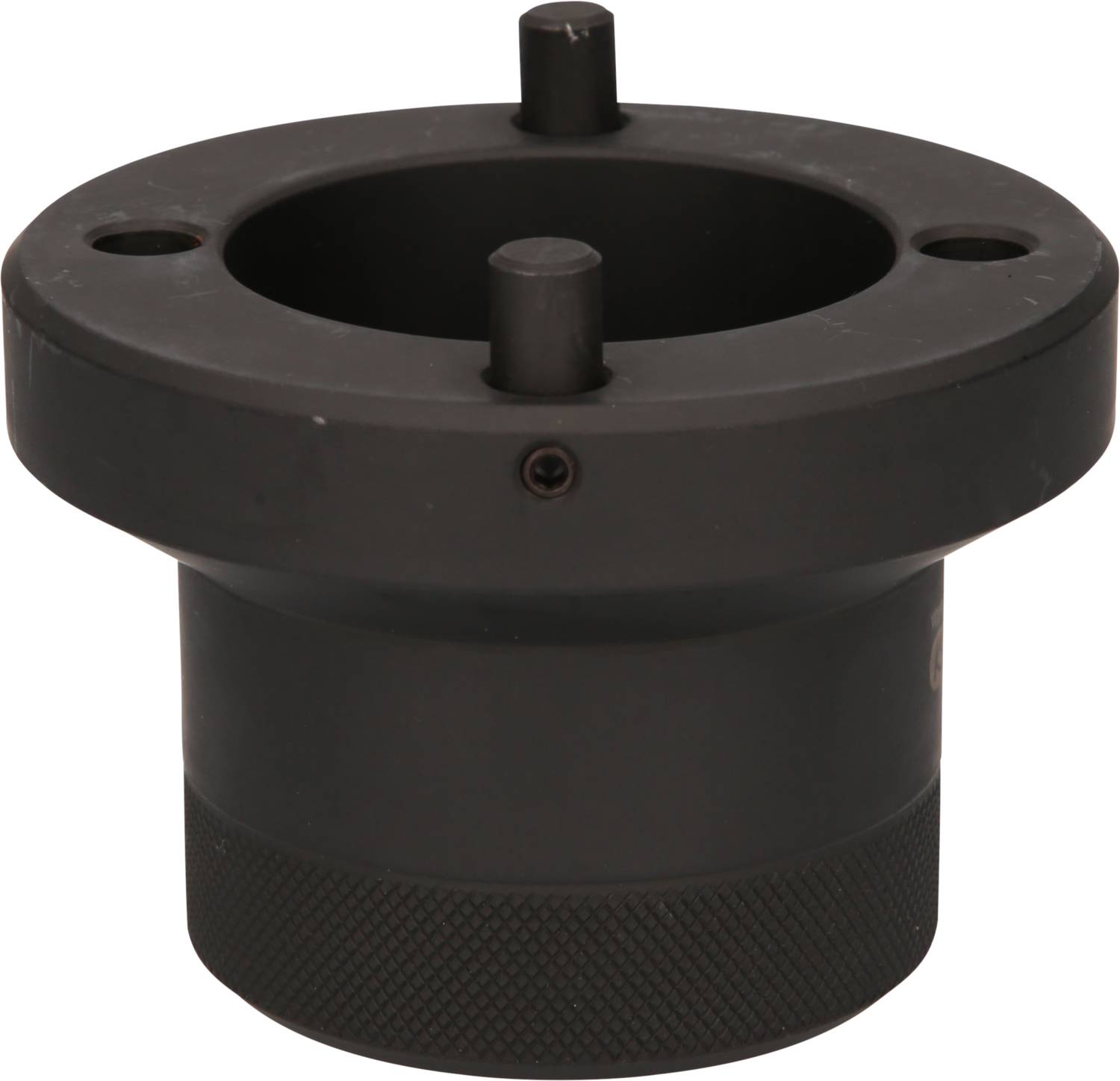 Ein schwarzes zylindrisches Metallteil mit flachem Ring und zwei hervorstehenden Stiften an der Oberseite, möglicherweise ein Maschinenteil.