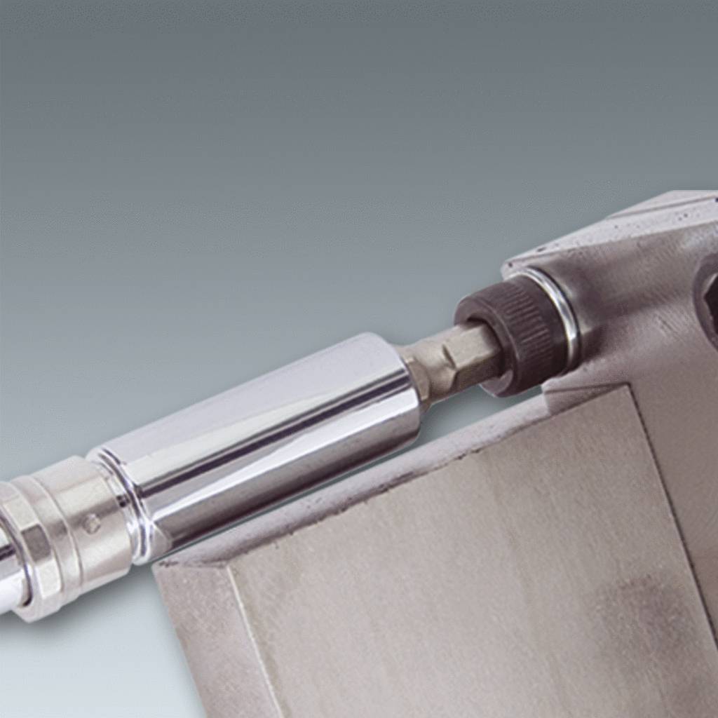 Metallischer Zylinder befestigt an einer Maschine mit grauem Hintergrund, zeigt technische Komponenten und mechanische Details.
