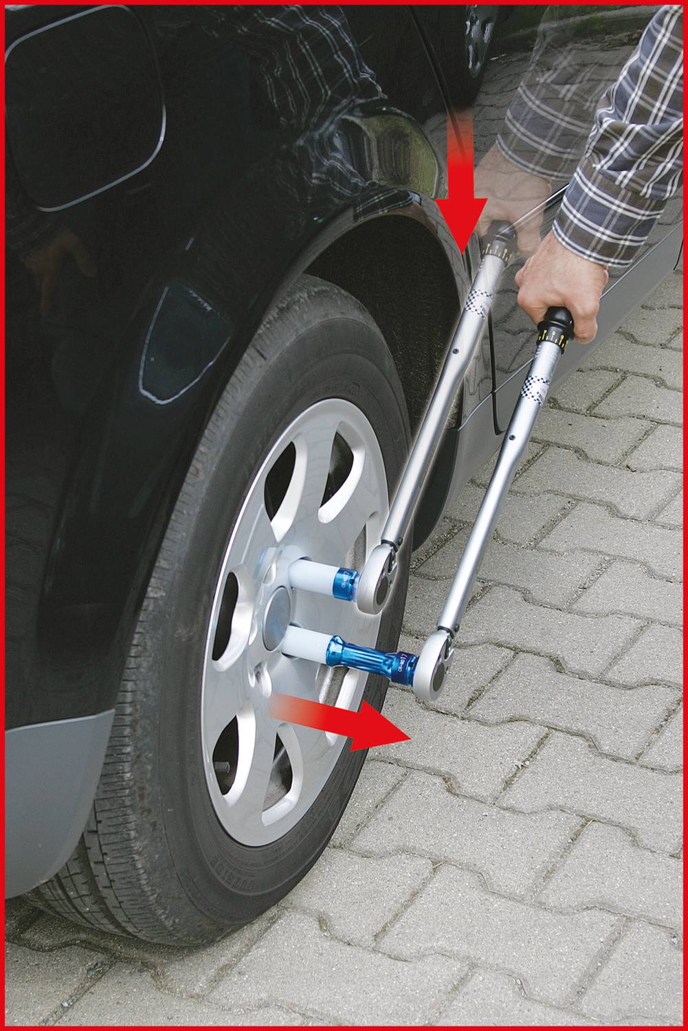 Eine Person zieht mit zwei Drehmomentschlüsseln am Rad eines Autos. Rote Pfeile zeigen die Richtung der Kräfte an.