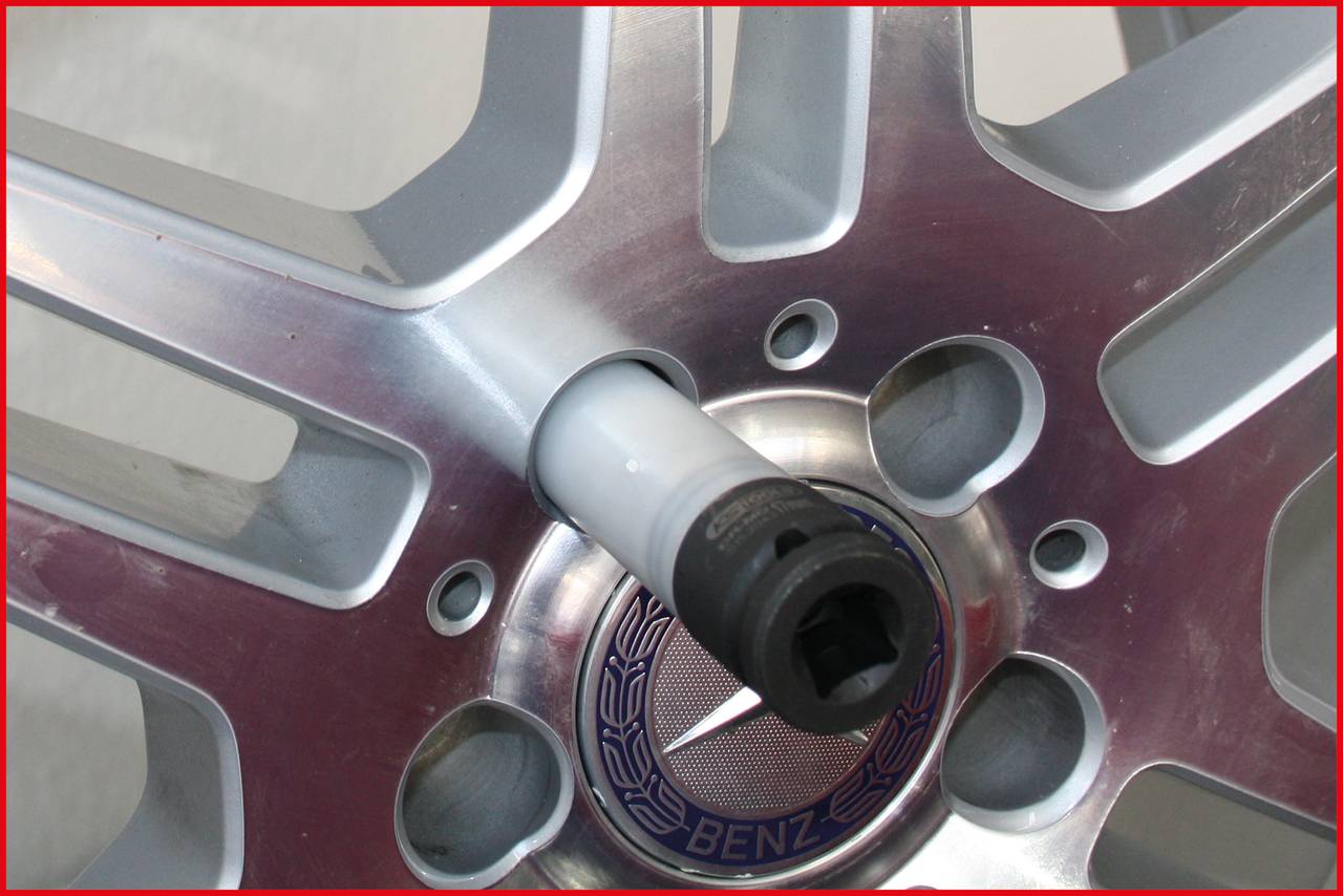 Nahaufnahme einer Autoreifenfelge mit silbernen Speichen. Ein Schraubenschlüssel ist in der Mitte angebracht, bereit für die Demontage.