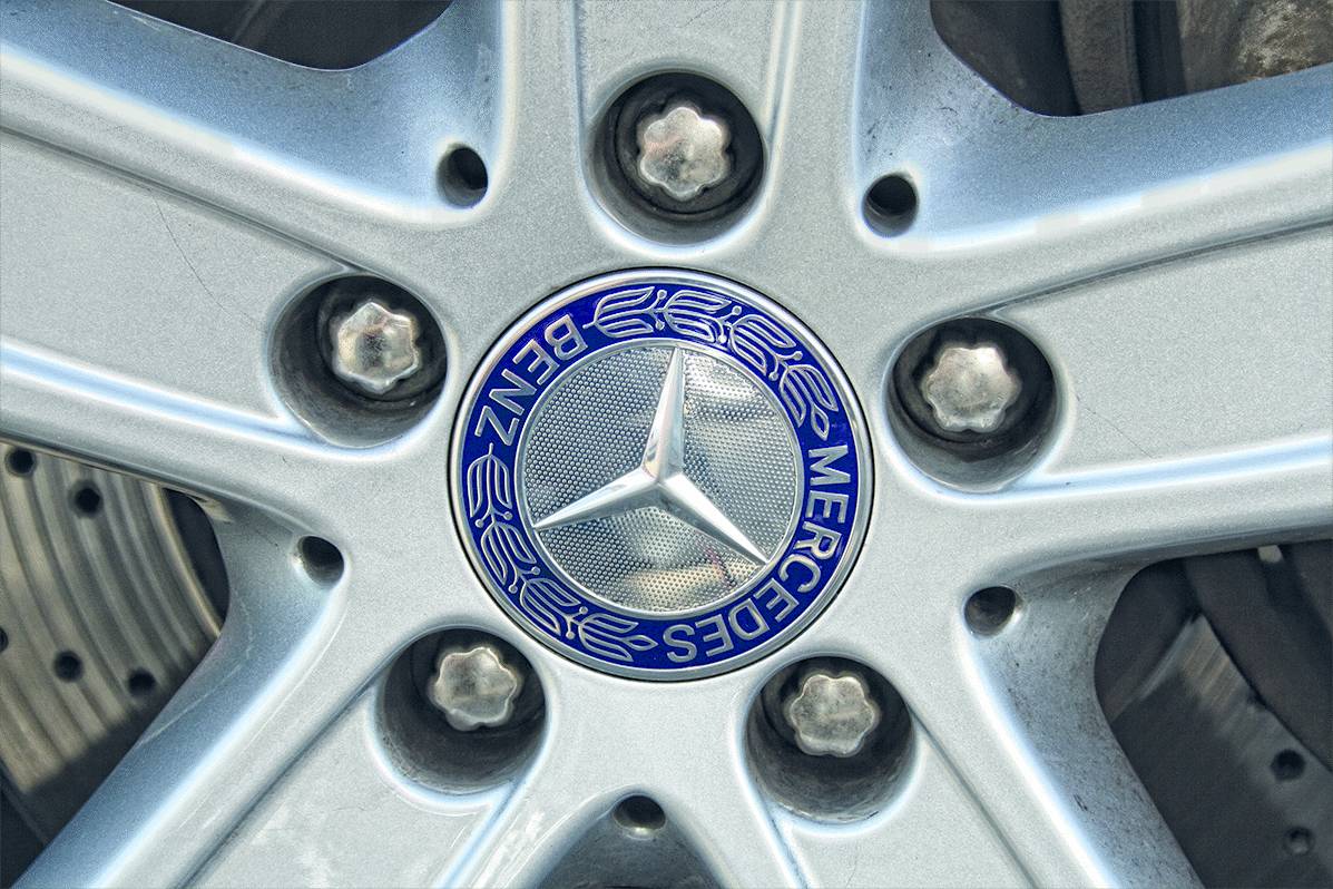 Autoreifen mit einer Mercedes-Benz-Felge. In der Mitte befindet sich das Mercedes-Logo, umgeben von fünf Radmuttern.
