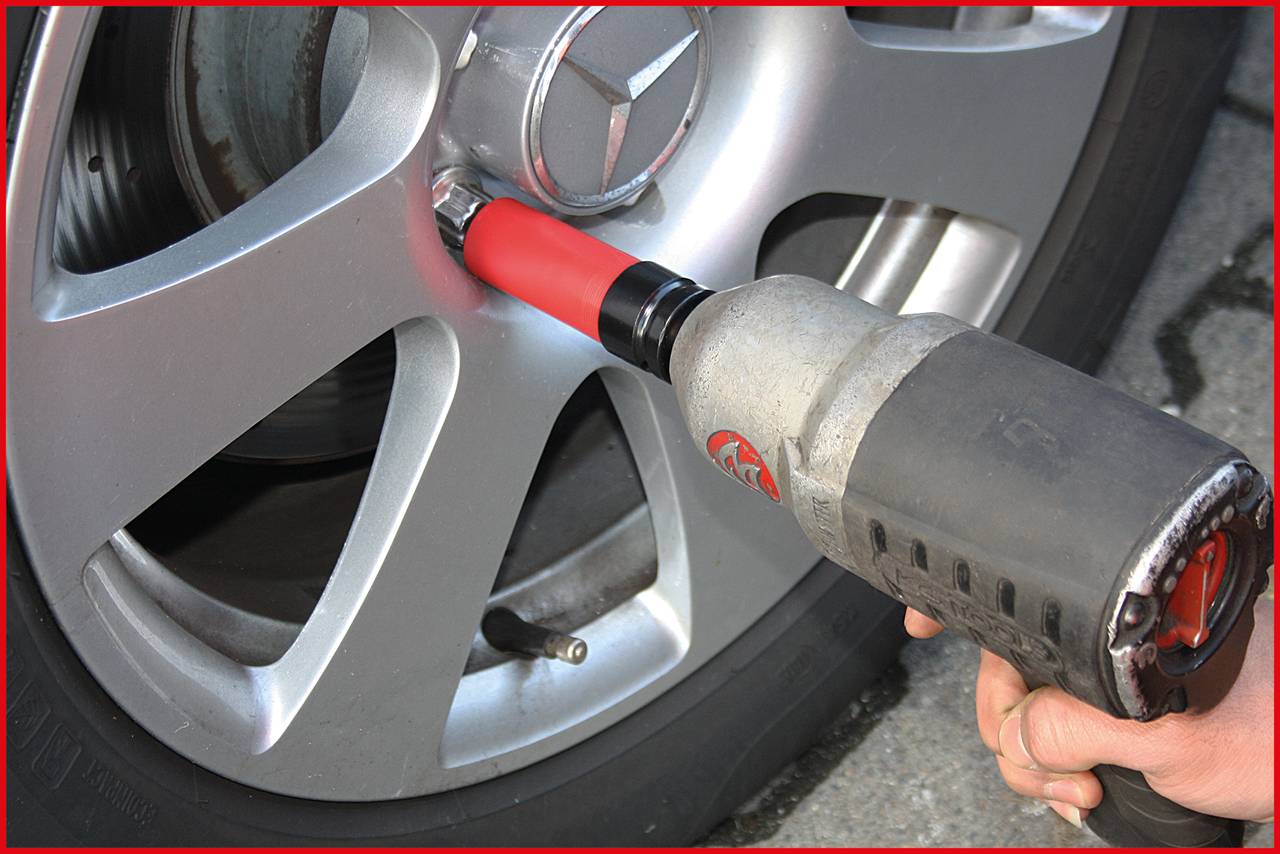 Eine Person nutzt einen Schlagschrauber, um eine Schraube an einer Autoreifenfelge festzuziehen.