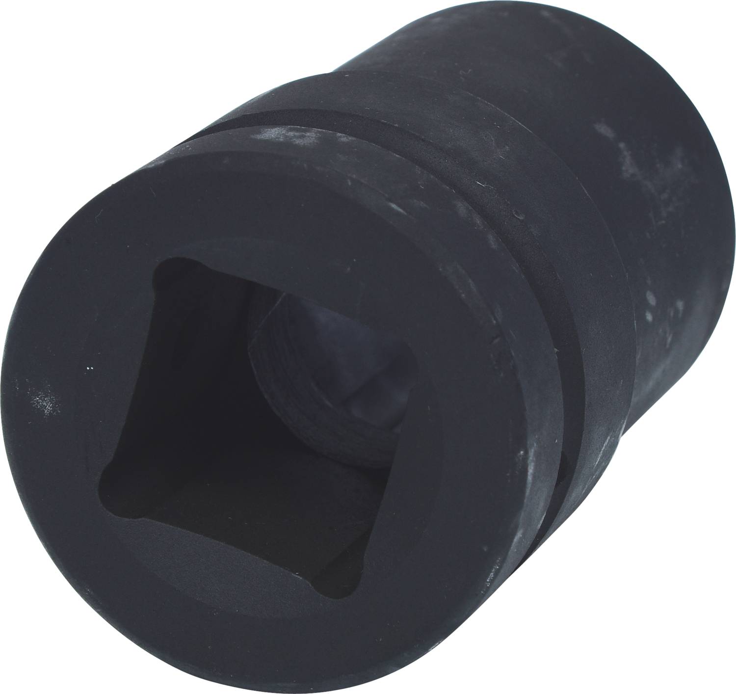 Eine schwarze, zylindrische Stecknuss mit quadratischer Öffnung liegt alleine und leicht schräg auf einer hellen Oberfläche.