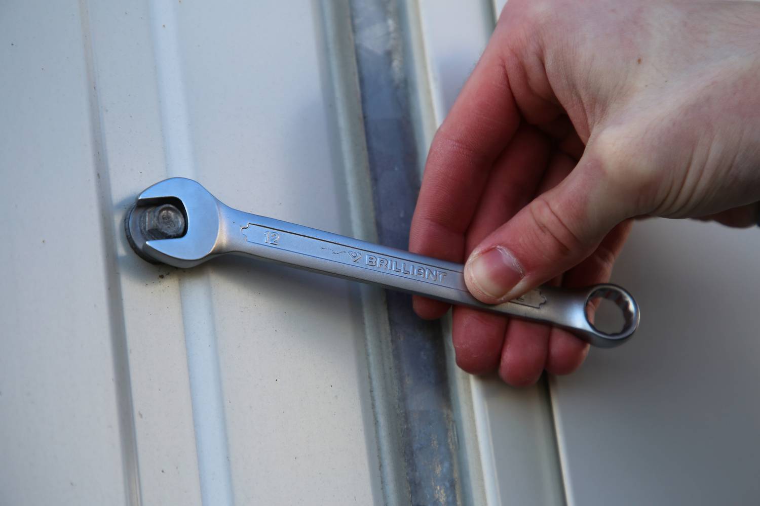 Eine Hand hält einen Schraubenschlüssel, der eine Schraube anzieht oder löst.