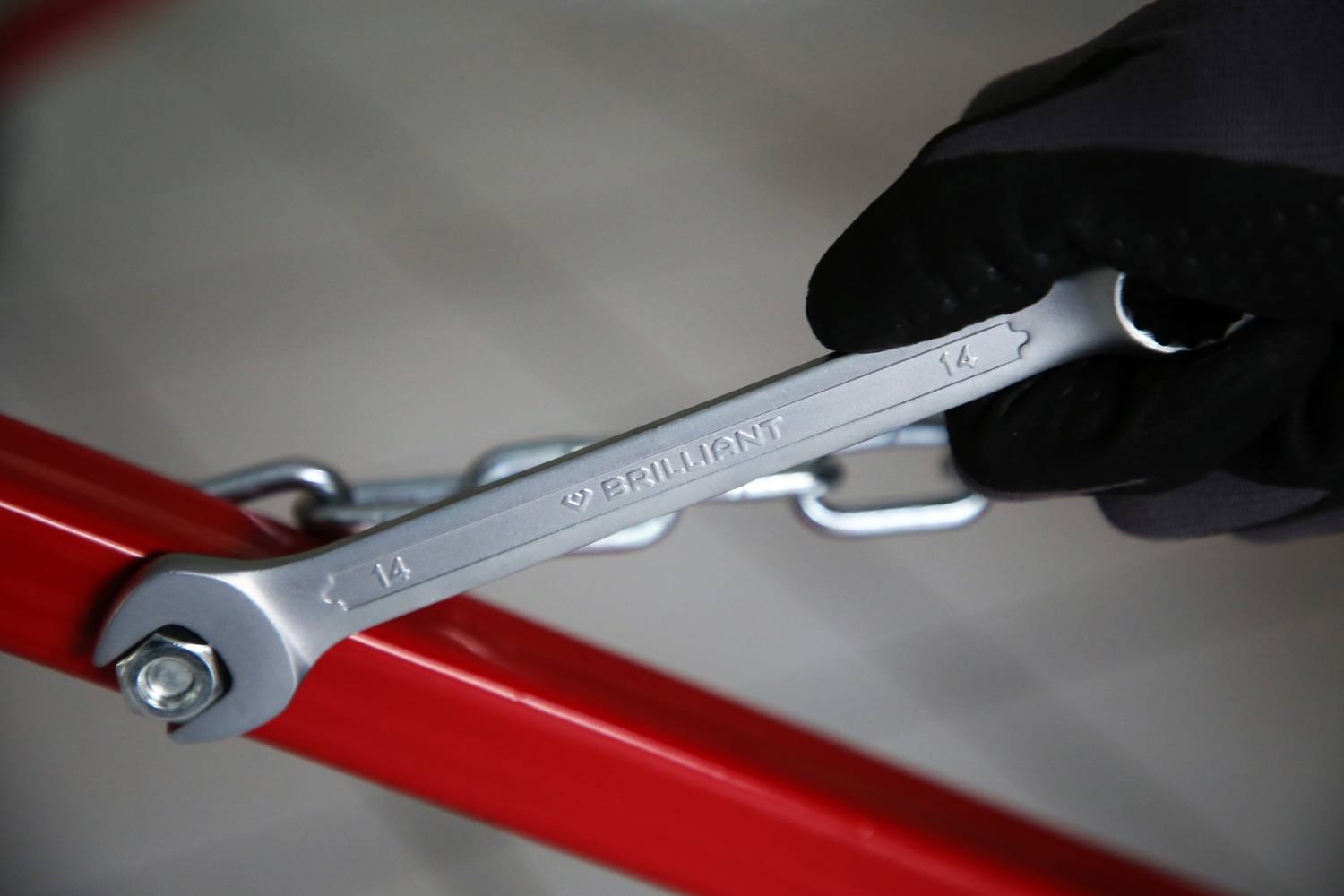 Eine Person mit einem schwarzen Handschuh zieht eine Schraube mit einem silbernen Schraubenschlüssel an, der auf 'BRILLIANT' markiert ist.