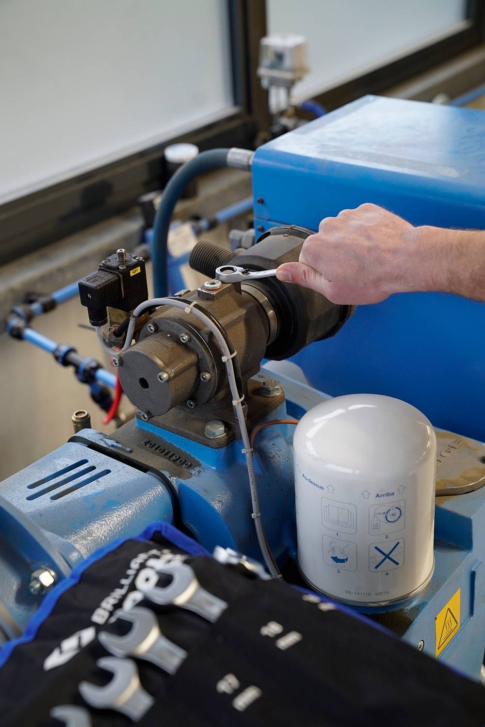 Ein Arbeiter stellt eine Maschine im Labor ein, mit verschiedenen Bedienelementen und Anzeigen an der blauen Anlage.