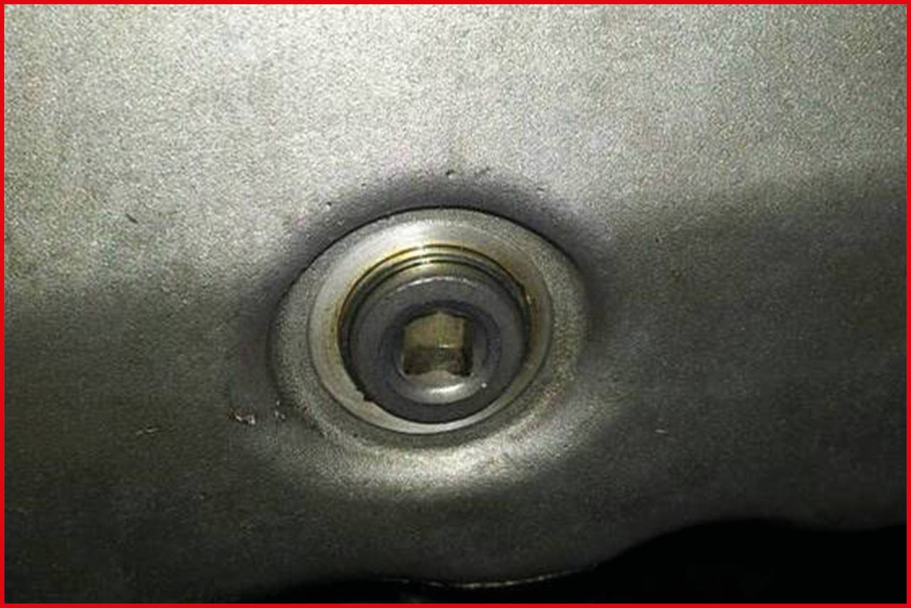 Nahaufnahme einer Metalloberfläche mit einer eingelassenen Schrauben- oder Bolzenöffnung in der Mitte.