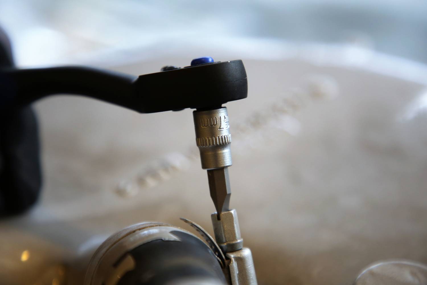 Nahaufnahme eines Bohrers, der in eine glatte Oberfläche bohrt. Ein schwarzer Griff und ein Metallbohrer sind im Fokus.