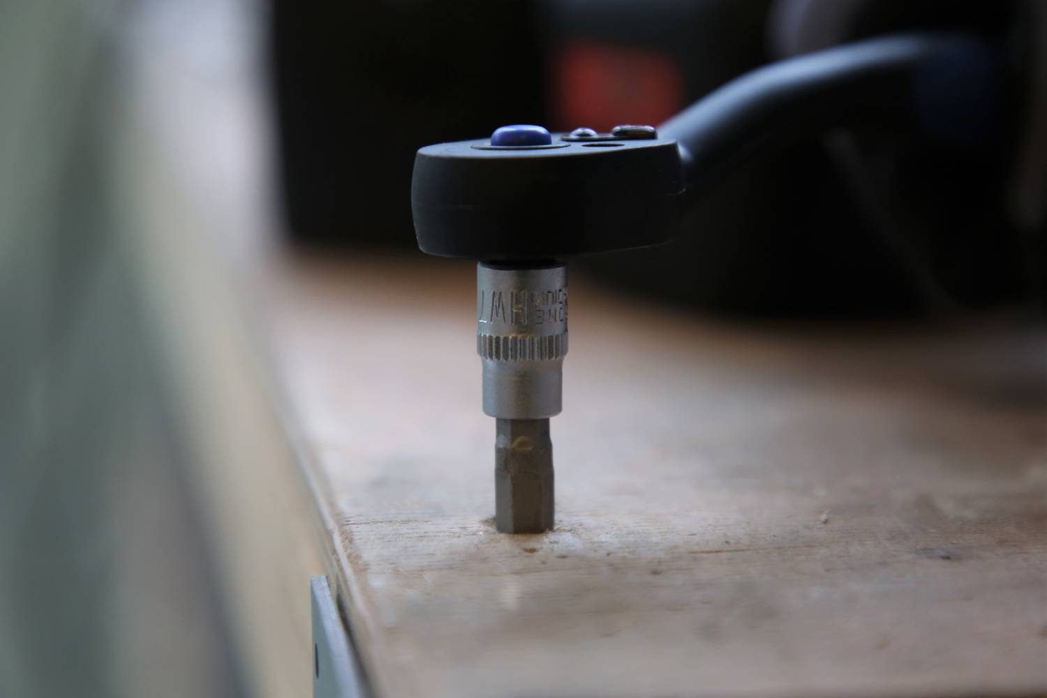 Akkuschrauber mit eingestecktem Bit liegt auf einer Werkbank. Fokus liegt auf dem Bit und dem Schnellspannfutter. Werkzeugumgebung.