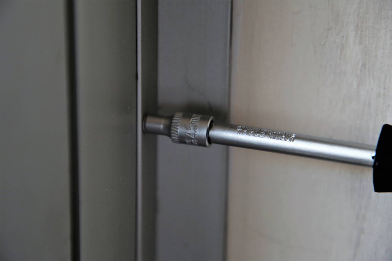 Silber-Schraubenschlüssel zieht Schraube in Metallplatte an.