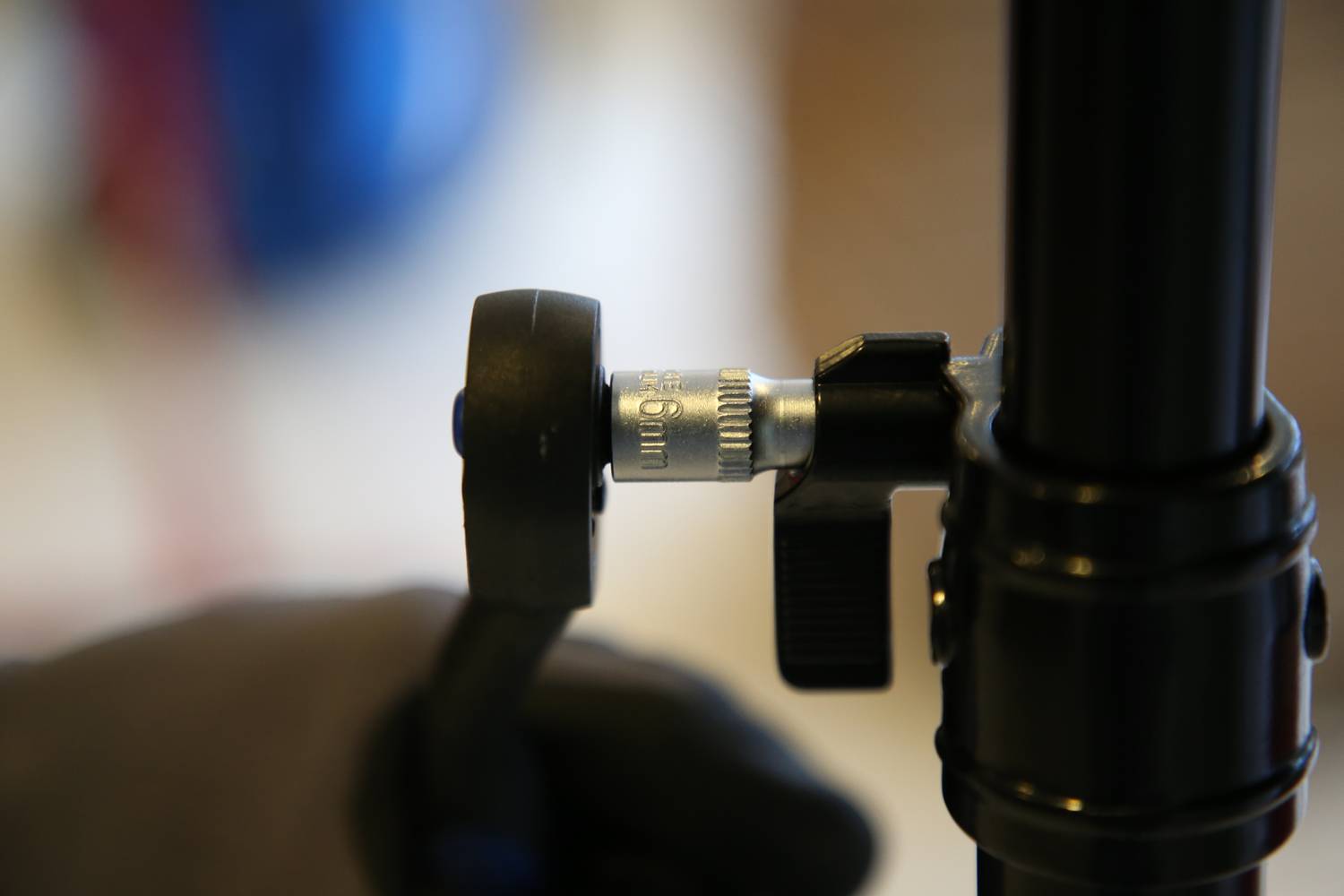 Person dreht einen Schalter an einem Stativ, Fokus auf das Einstellrädchen im Vordergrund. Der Hintergrund ist unscharf.