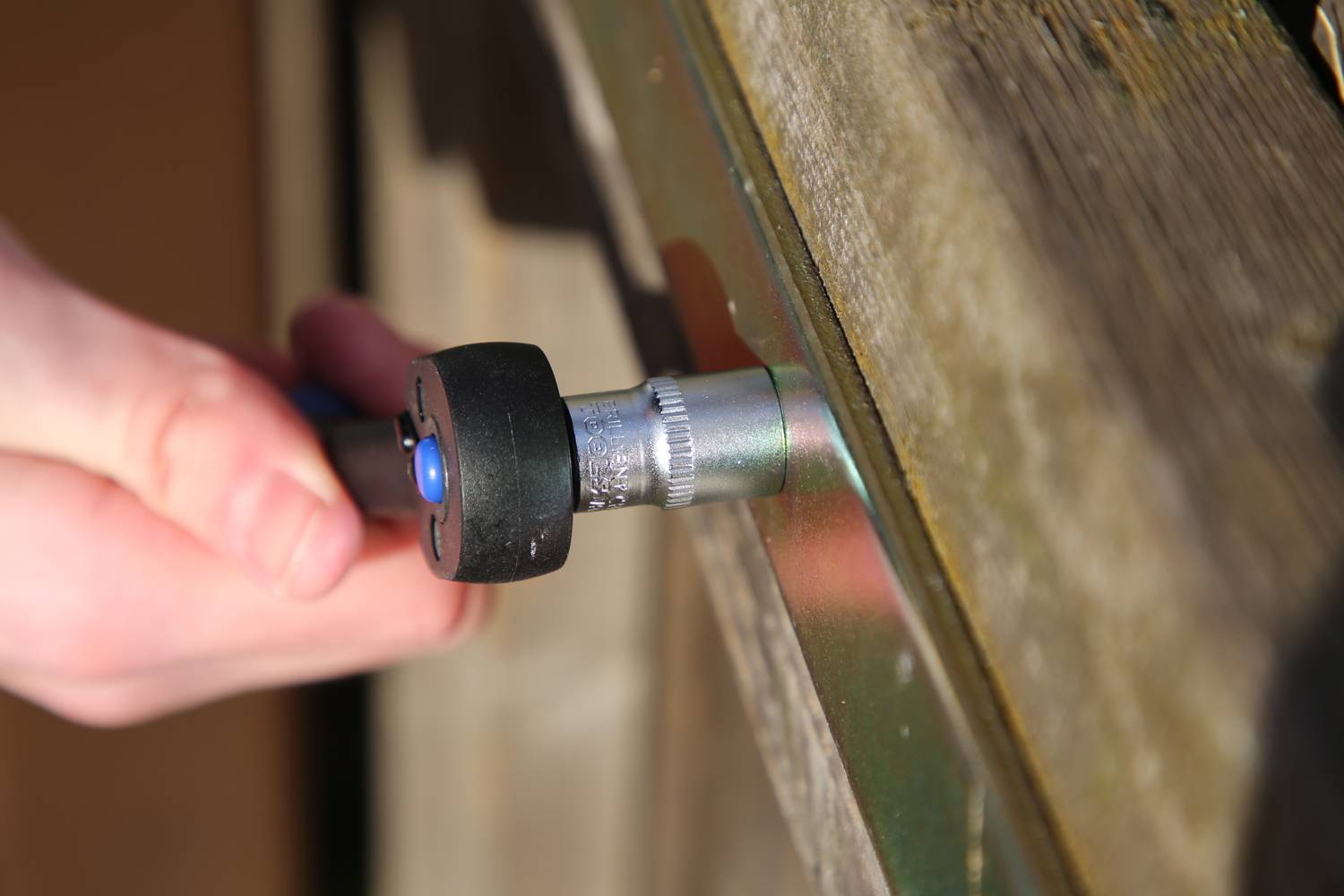 Eine Hand hält einen Schraubendreher, der eine Schraube in eine Holzoberfläche dreht.