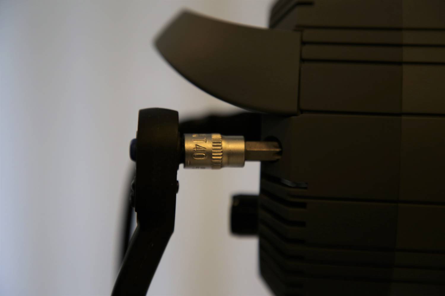 Ein schwarzes Gerät mit einem eingesteckten Kabel, das von einer Metallschraube mit der Aufschrift 'AL 10' gehalten wird.