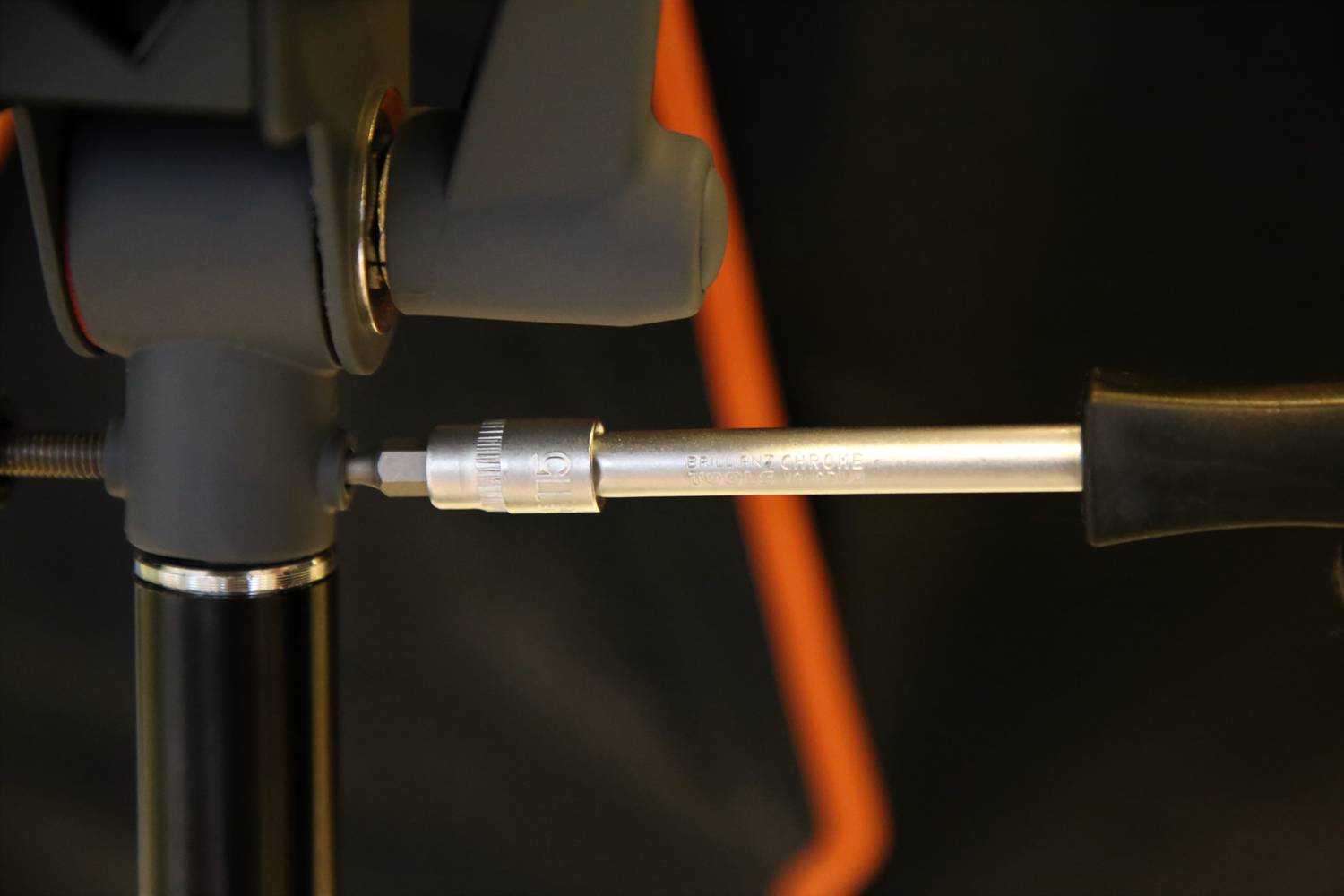 Nahaufnahme eines Stativs mit grauen und schwarzen Komponenten, Fokus auf die Befestigung und Einstellmechanismus.