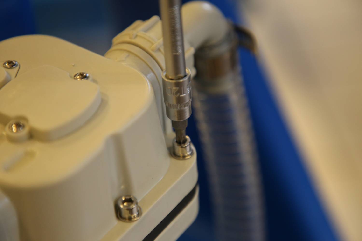 Nahaufnahme eines Werkzeugs, das eine Schraube in ein technisches Gerät eindreht, mit fokusiertem Blick auf Mechanismus und Material.