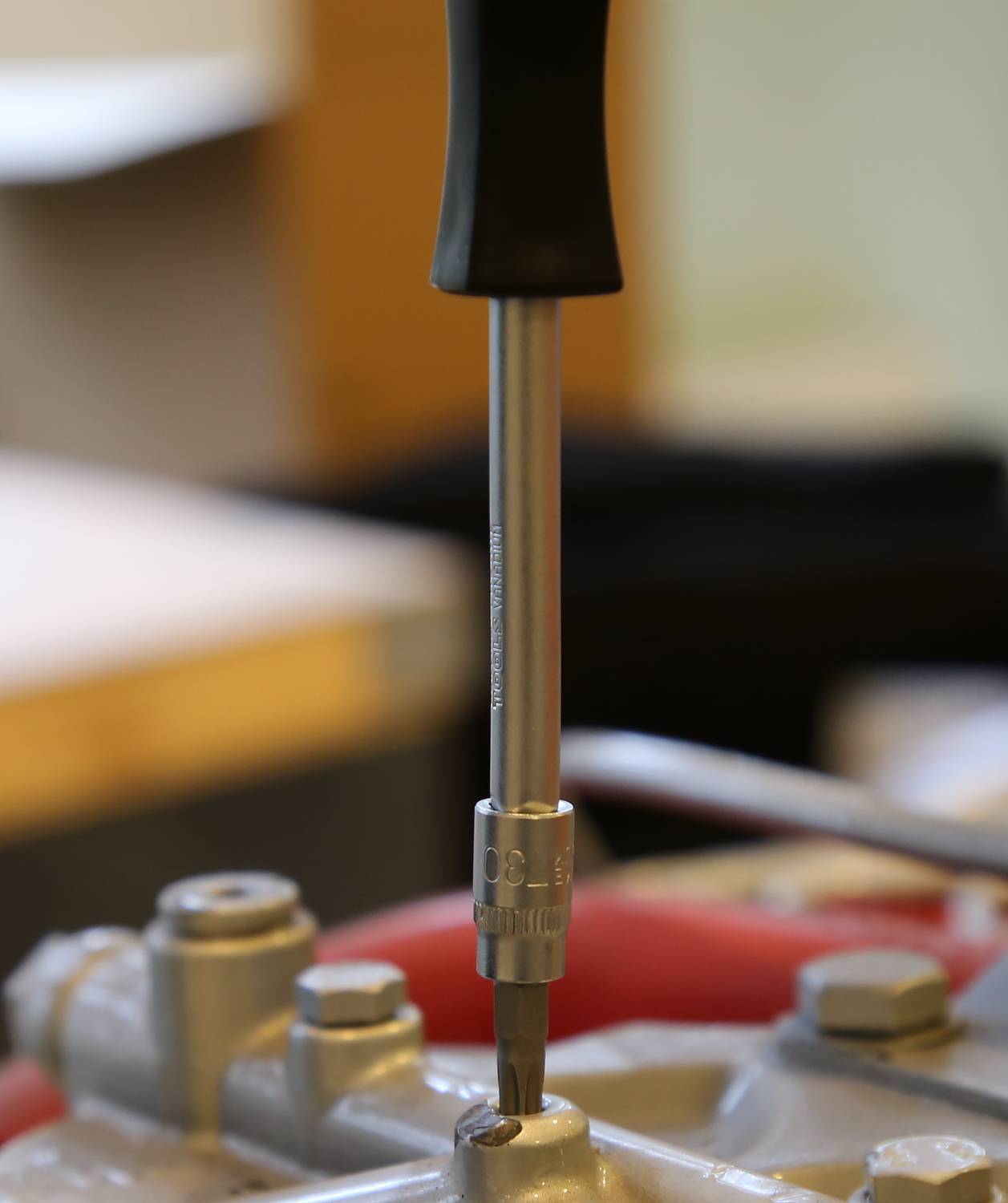 Ein Schraubendreher mit schwarzem Griff wird verwendet, um eine Schraube an einer Metallfläche zu befestigen.