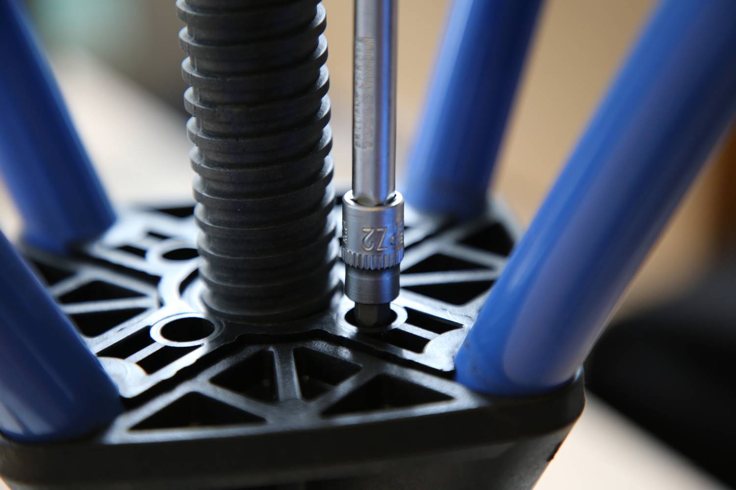 Montage eines 3D-Druckers: Eine Schraube wird mit einem Inbusschlüssel befestigt, um einen blauen Rahmen an der Basis zu stabilisieren.