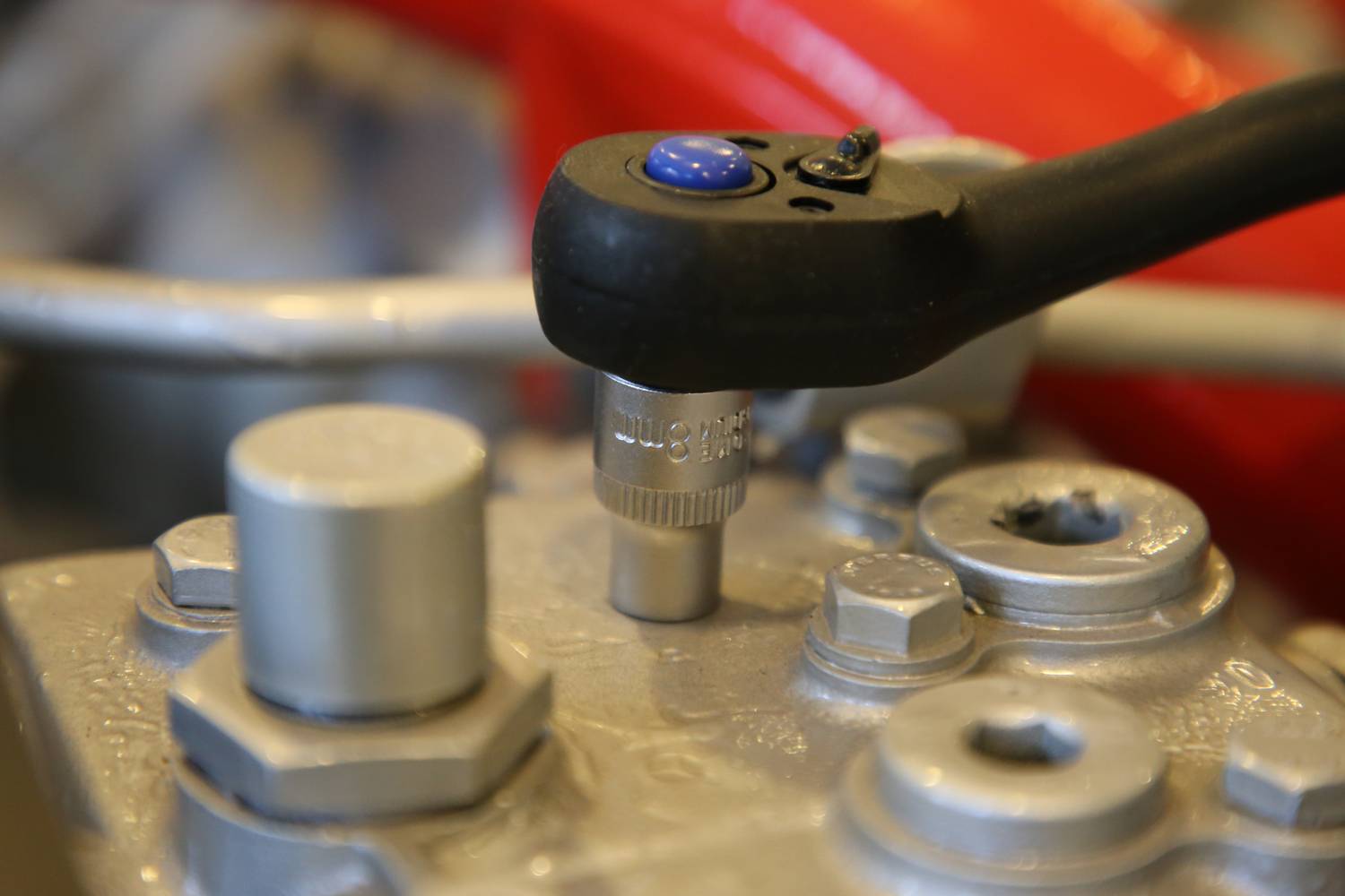 Ein Drehmomentschlüssel zieht eine Schraube in einem mechanischen Bauteil an. Nahaufnahme zeigt Details der Metallverbindungen.